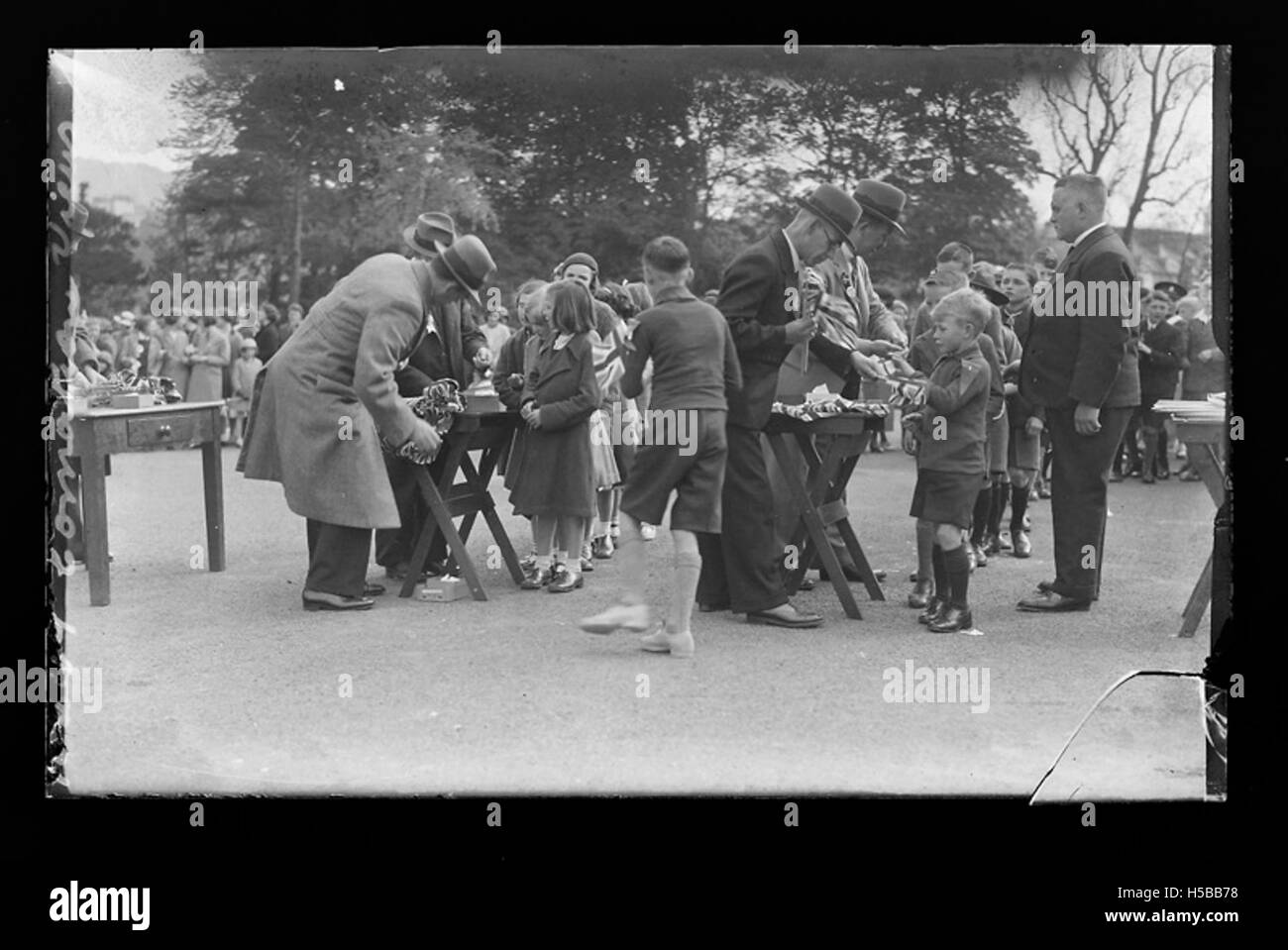 Pendant le couronnement du roi George VI, des enfants sont vus recevoir des drapeaux pour célébrer l'événement. Le couronnement de 1937 marque le début du règne du roi George VI à la suite de l'abdication de son frère, le roi Édouard VIII Banque D'Images