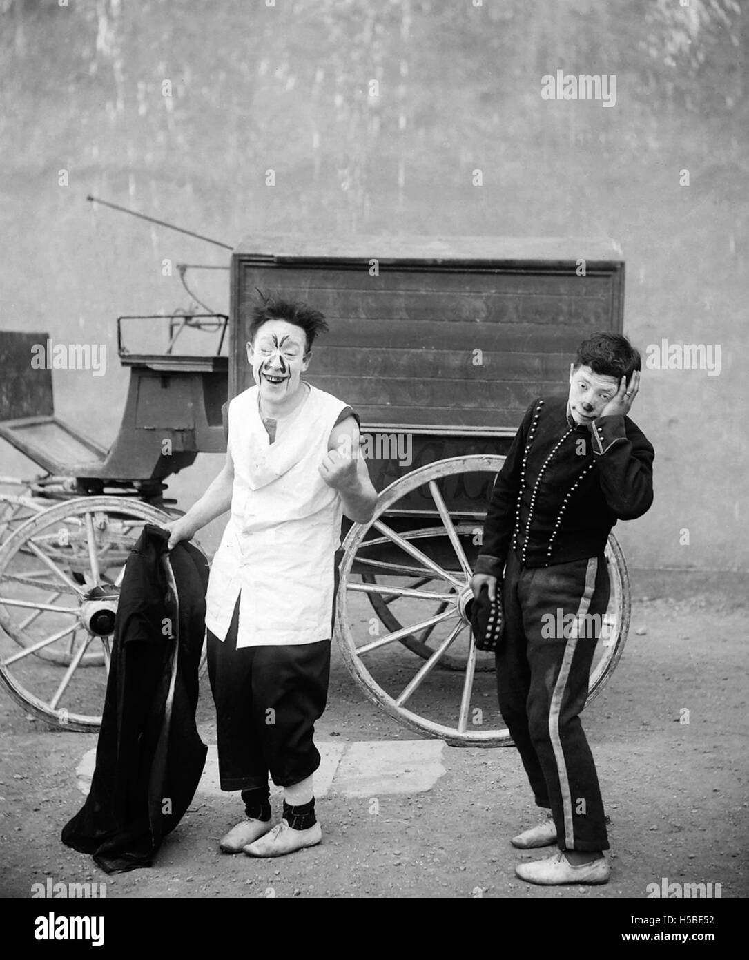 Photographie ou image représentant deux clowns devant un wagon, probablement prise lors d'un événement de cirque ou de carnaval, capturant la nature légère du spectacle. Banque D'Images