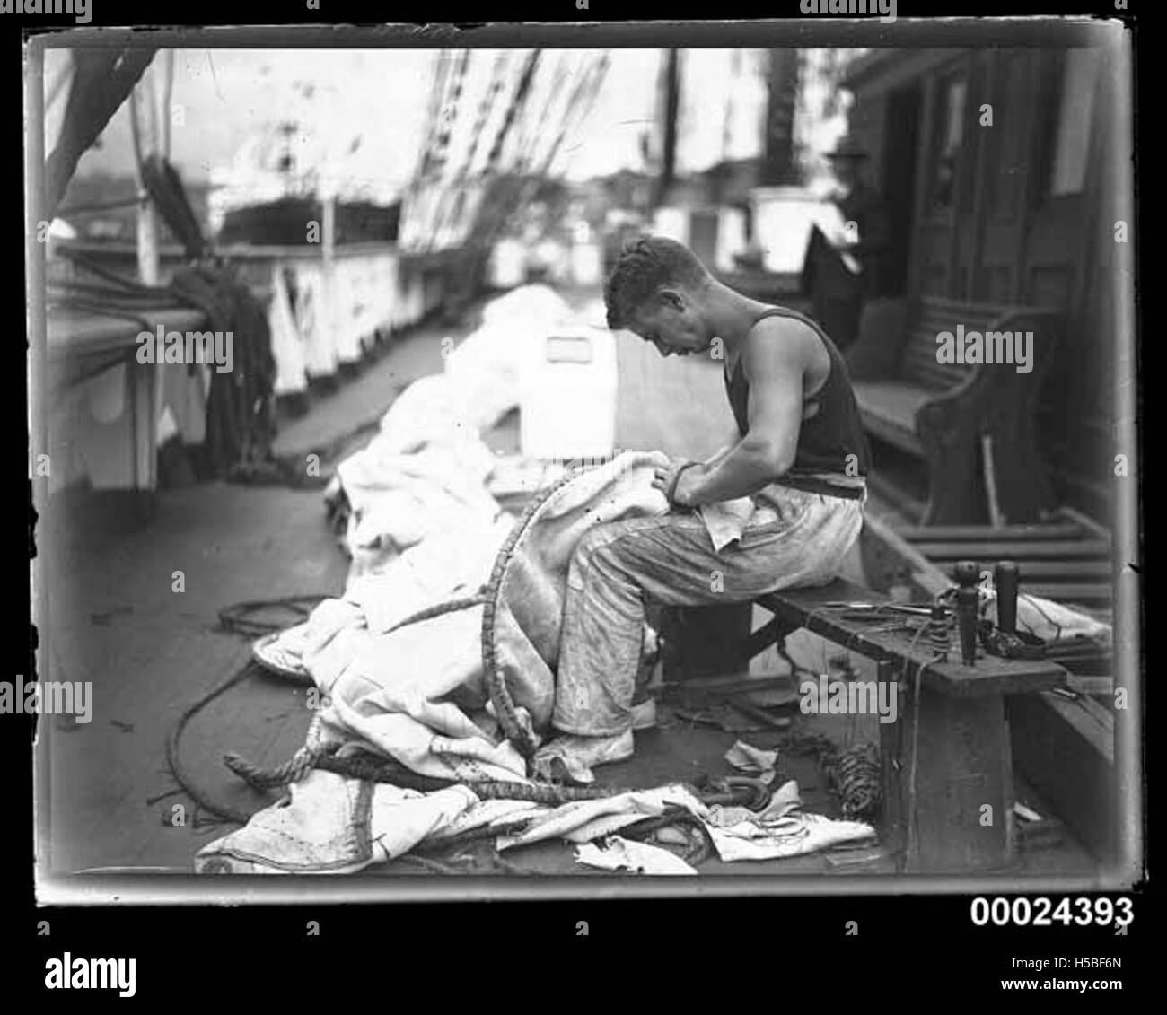 Une photographie d'un membre d'équipage à bord du navire Magdalene Vinnen, préparant les voiles sur le pont, montrant l'activité maritime et les tâches de l'équipage impliquées dans la navigation. Banque D'Images