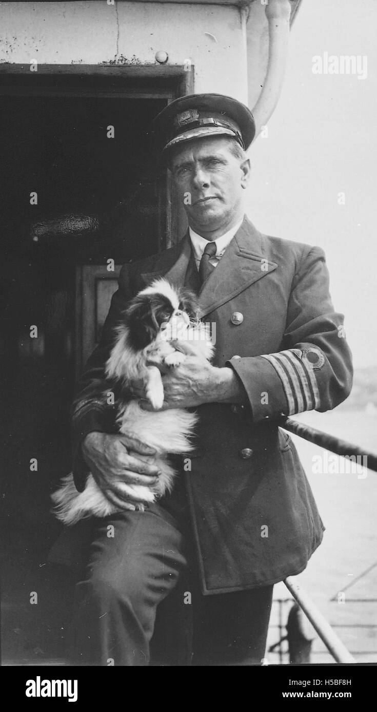 Portrait du capitaine du SS Purley, accompagné de son épagneul japonais, pris entre 1906 et 1919, capturant un moment personnel du début du XXe siècle. Banque D'Images