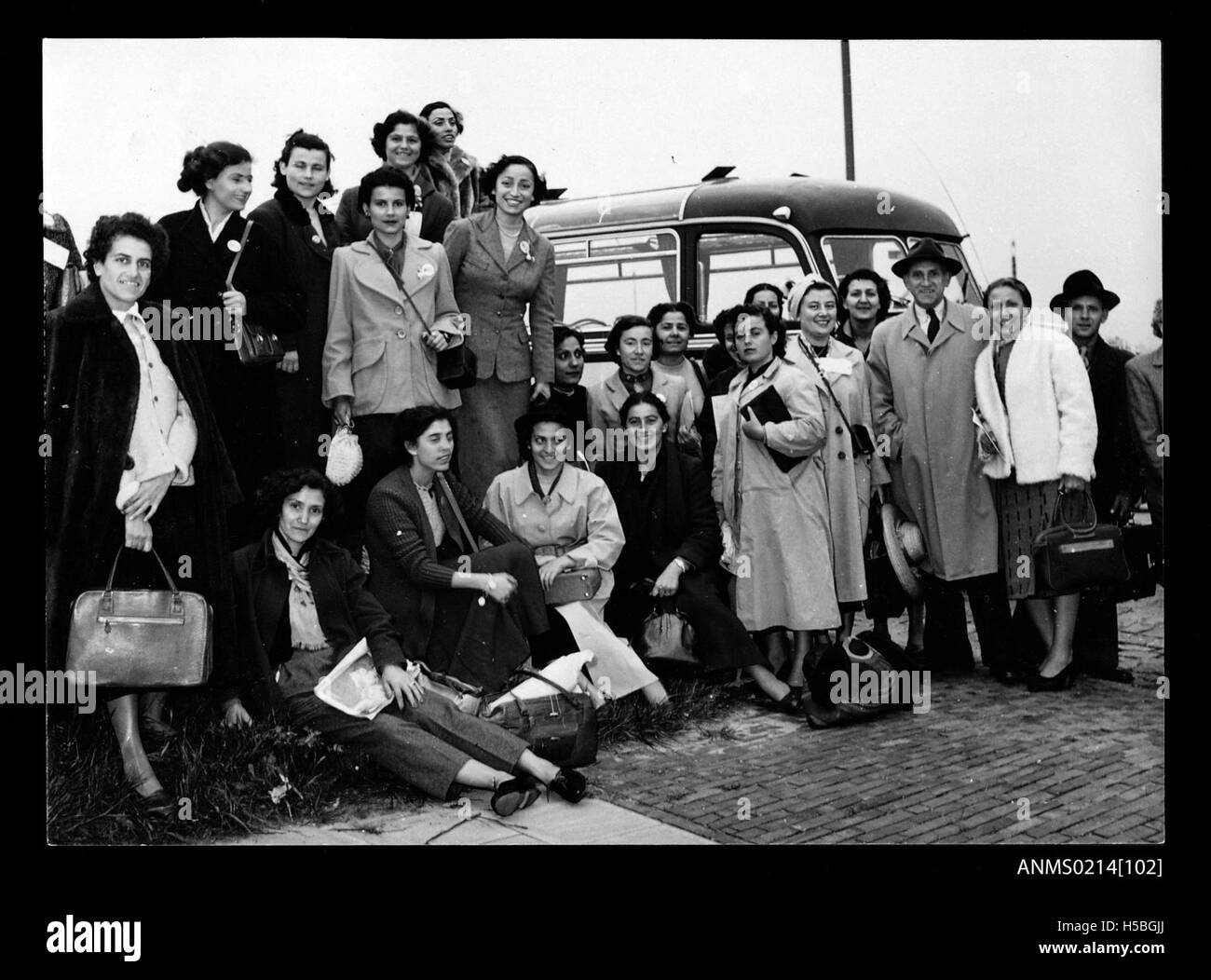 Un groupe de jeunes femmes est montré près d'un bus, probablement en train de migrer vers l'Australie. Cette image reflète l'ère de la migration de masse vers l'Australie, en particulier au début du XXe siècle, lorsque de nombreuses femmes ont voyagé pour commencer une nouvelle vie en Australie. Banque D'Images