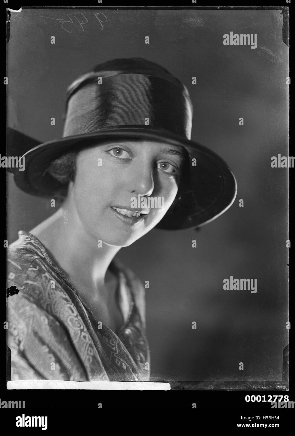 Ce portrait représente une jeune femme non identifiée, mettant en valeur les techniques de photographie du début du XXe siècle. L'image se concentre sur les traits du visage et la tenue vestimentaire du sujet, typiques de la mode et du style de l'époque. Banque D'Images