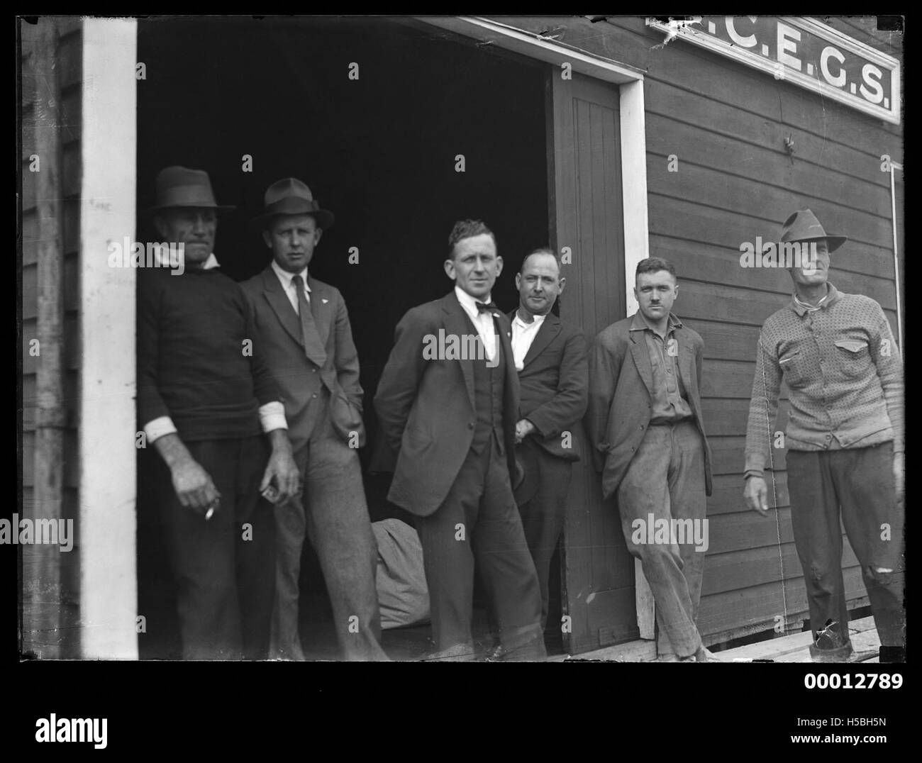 Photographie montrant six hommes posant devant le hangar à bateaux de la Sydney Church of England Grammar School à Berry's Bay, reflétant les traditions et les activités maritimes de l'école. Banque D'Images