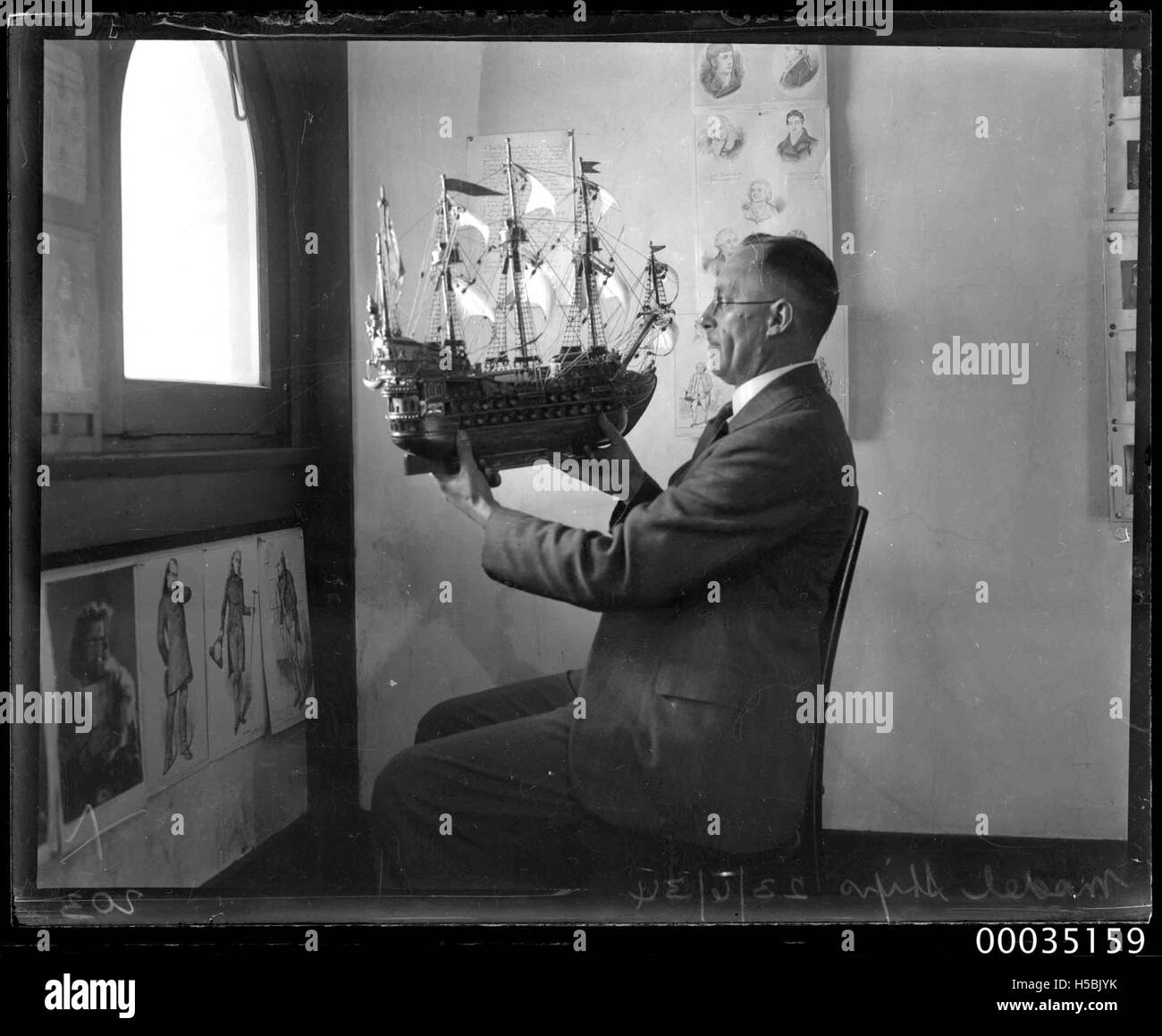 Un homme est représenté tenant une maquette d'un galion du XVIe siècle, avec l'image datée du 23 juin 1934. Cette photographie fait partie de la collection Hood, offrant un aperçu des bateaux maritimes historiques de l'ère de la voile. Banque D'Images