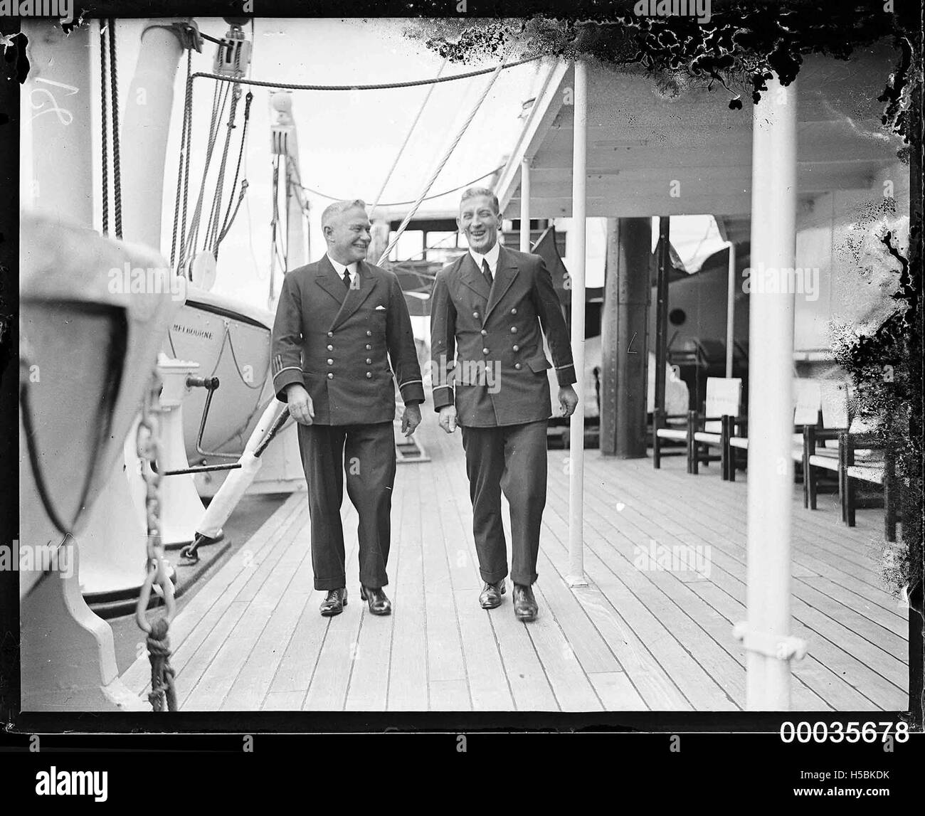 Deux officiers à bord du SS ORUNGAL, un navire du début du XXe siècle, marchant sur son pont vers 1930. L'image fait partie de la COLLECTION HOOD, documentant la vie maritime et les officiers de marine pendant cette période. Banque D'Images
