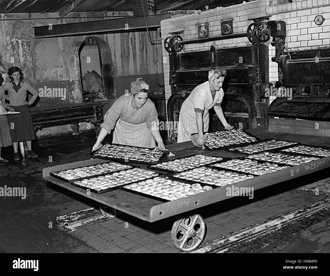 Cette photographie montre des ouvriers fabriquant des gâteaux Eccles à l’usine Arran à y Bala. Les gâteaux Eccles sont une pâtisserie britannique traditionnelle remplie de groseilles et faite de pâte feuilletée, souvent dégustée en collation ou en dessert. Banque D'Images