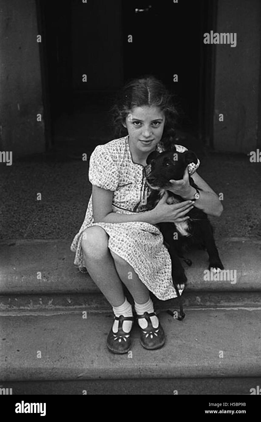 Un portrait de Dolly Morris, debout sur Llanfair Road à Newtown, accompagnée de son chien. La photographie capture un moment personnel du début du XXe siècle, mettant en valeur la vie quotidienne et le lien entre la femme et son animal de compagnie. Banque D'Images