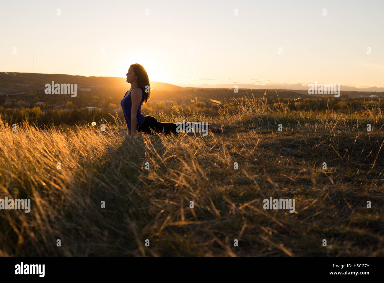 Woman doing yoga cobra posent pendant le coucher du soleil Banque D'Images