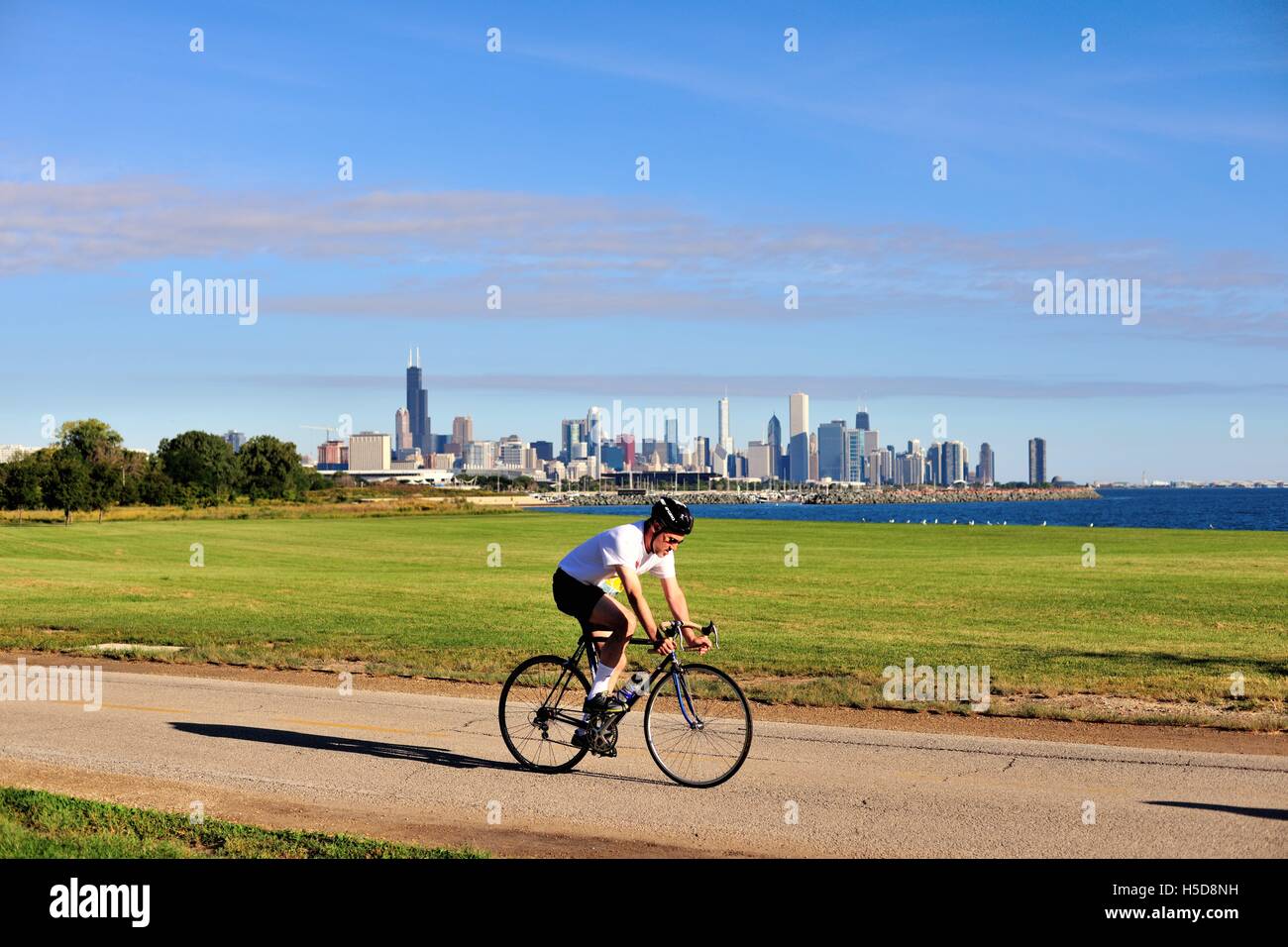 Un cycliste solitaire pédaler le long d'un chemin sur le côté sud avec une vue panoramique de la ville. Chicago, Illinois, USA. Banque D'Images