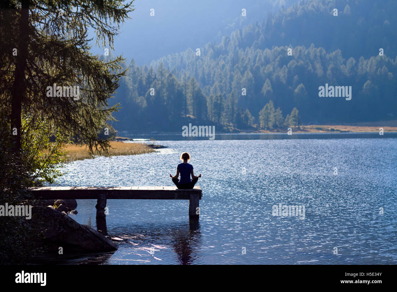 Pretty woman practicing yoga at a lake Banque D'Images