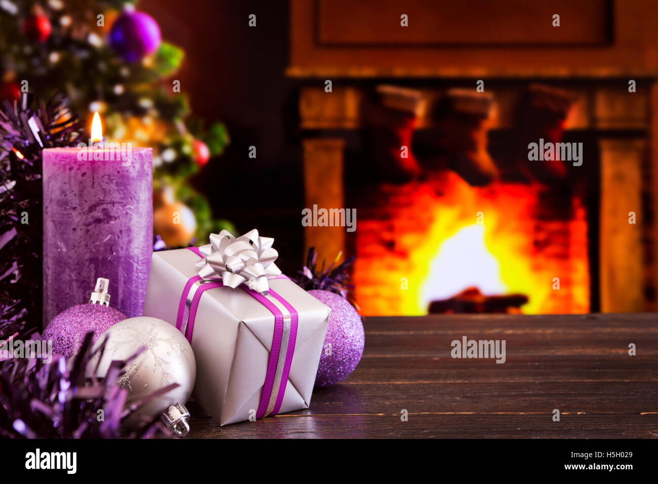 Décorations de Noël, un cadeau et des bougies devant une cheminée. Un feu  brûle dans la cheminée et des bas de Noël ar Photo Stock - Alamy
