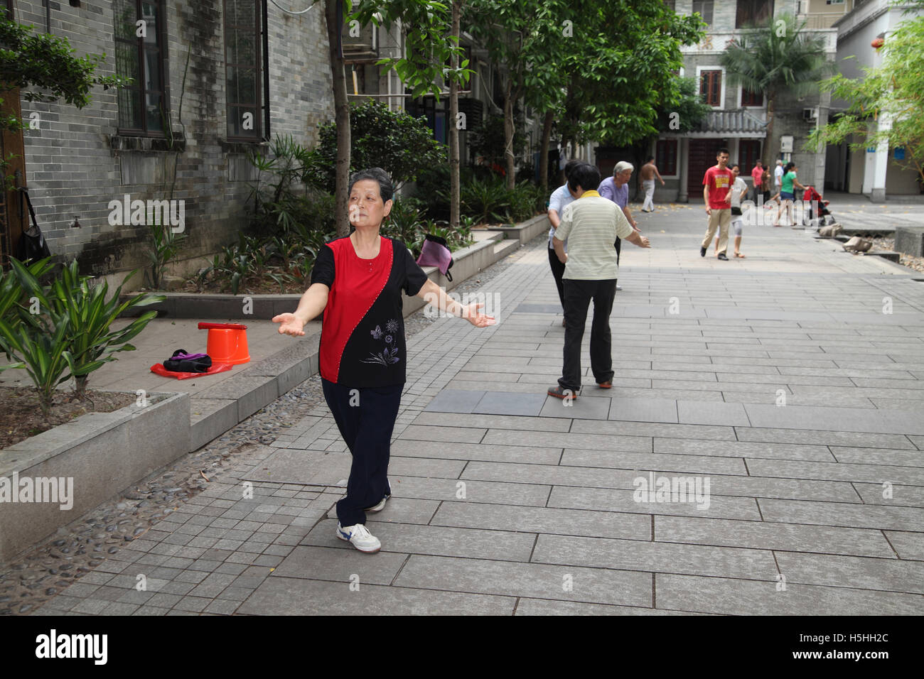 Une vieille femme à la retraite et d'autres personnes ne le Tai Chi dans un parc public que les gens passer. Liwan Lake Park, Guangzhou, Chine. Banque D'Images Une vieille femme à la retraite et d'autres personnes ne le Tai Chi dans un parc public que les gens passer. Liwan Lake Park, Guangzhou, Chine. Banque D'Images