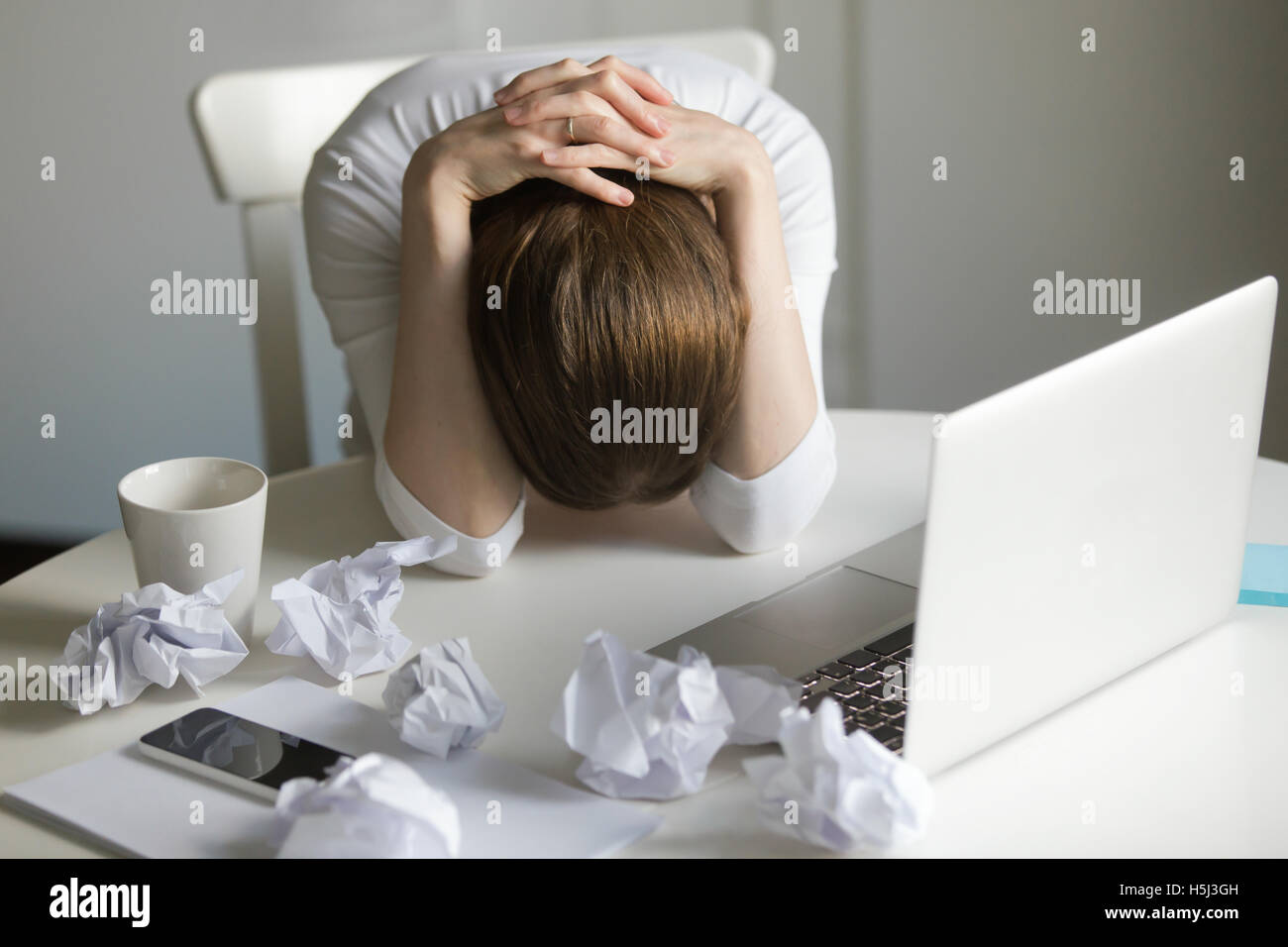 Portrait de femme saisissant sa tête près de l'ordinateur portable Banque D'Images