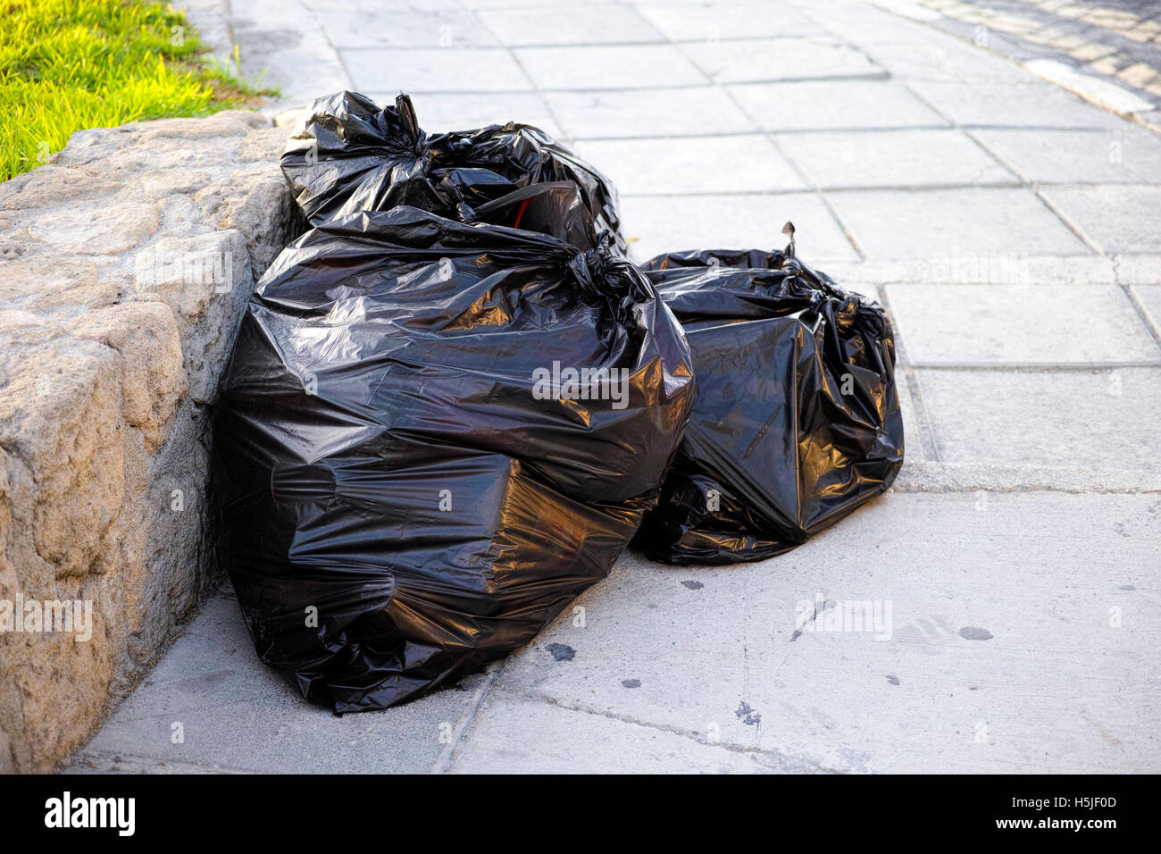 Sacs poubelles en plastique noir complet dans la rue Banque D'Images