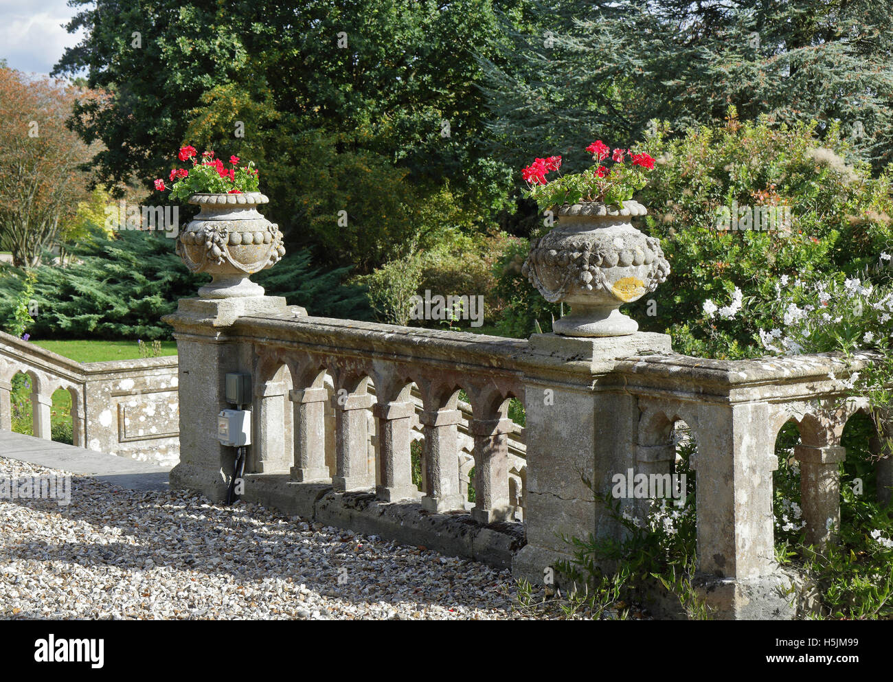 Balustrade dans un jardin paysage formel avec les semoirs de pierres ornementales remplis de géraniums Banque D'Images