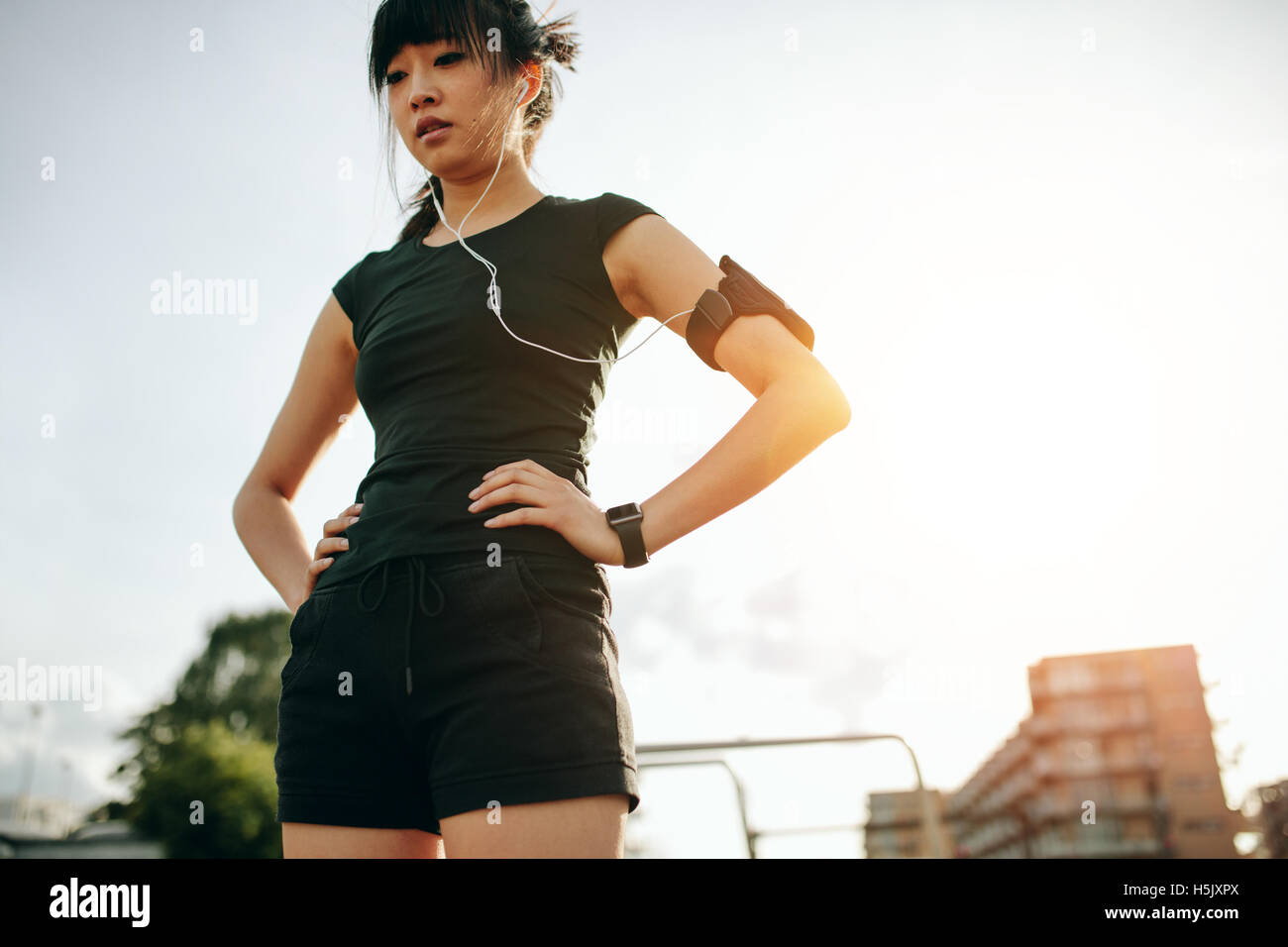 Coup de jeune femme chinoise en faisant une pause au cours d'un jogging matinal. Femme debout à l'extérieur de remise en forme avec ses mains sur les hanches. Banque D'Images