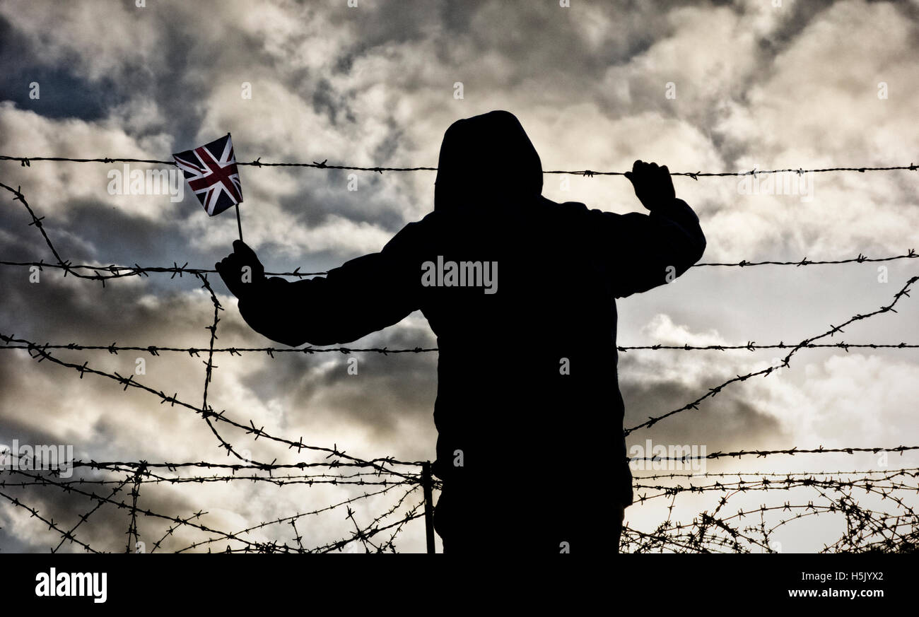 Vue arrière d'un homme portant veste holding Union Jack Flag à la recherche à travers des barbelés à clôture. Brexit, concept de l'immigration... Banque D'Images