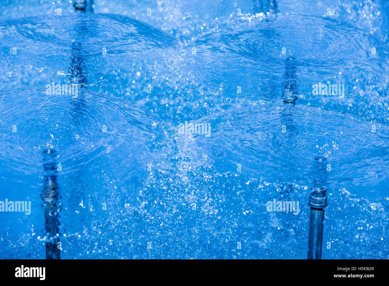 Un écran circulaire de jets d'eau en spray bleu fontaine Banque D'Images