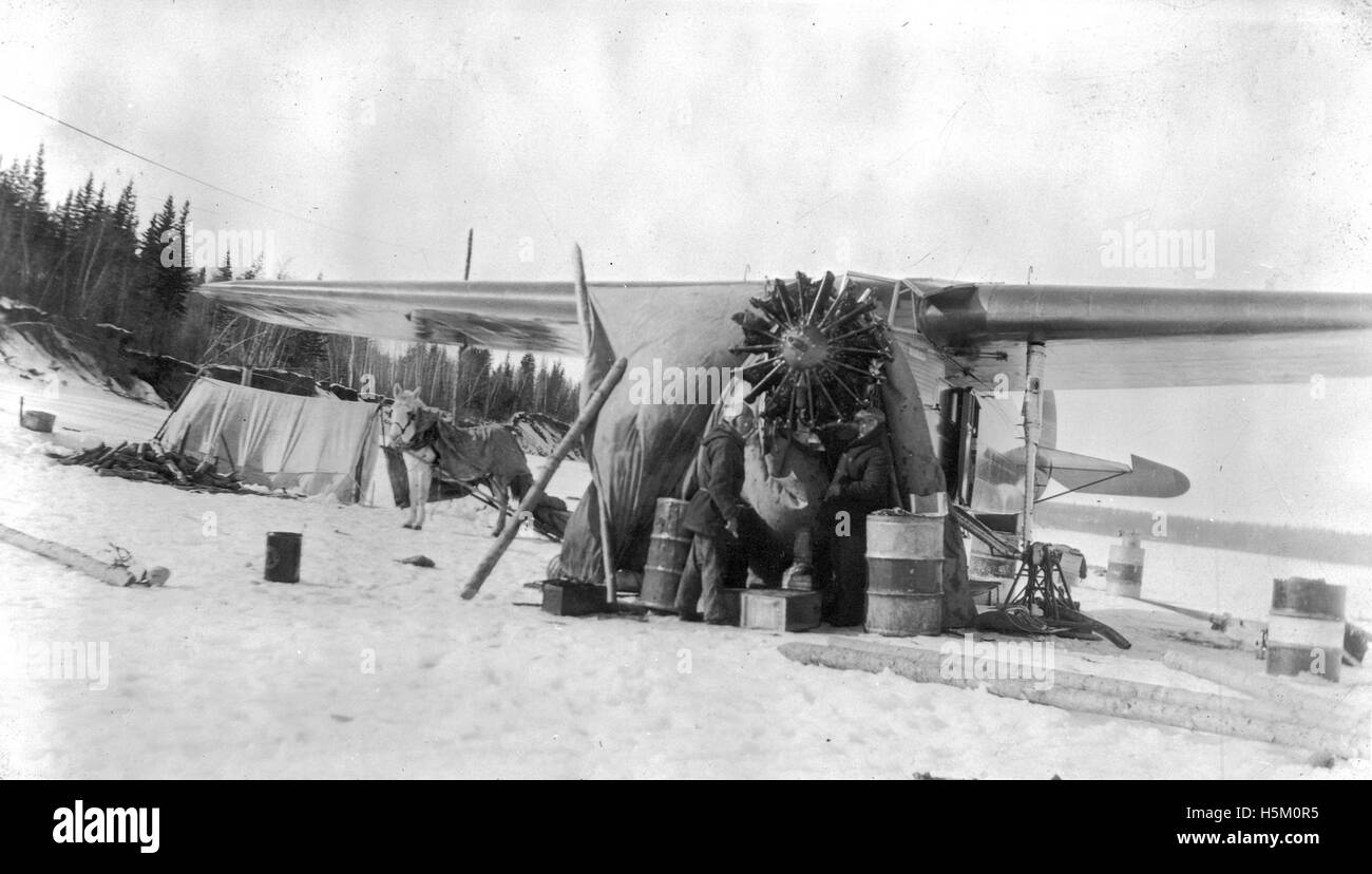 La photographie montre un moteur d'avion en cours de changement dans des conditions hivernales difficiles. La scène illustre les défis de la maintenance aéronautique par temps froid, en mettant l'accent sur les compétences techniques requises pour maintenir les aéronefs opérationnels dans des conditions extrêmes. Banque D'Images