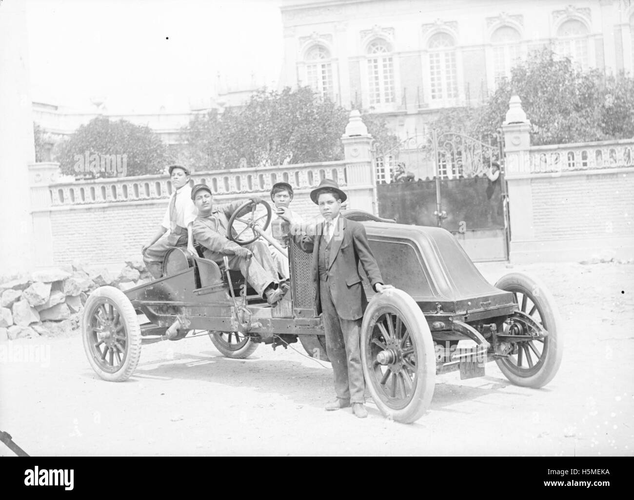 [Les hommes et les garçons avec la voiture en face du bâtiment] Banque D'Images