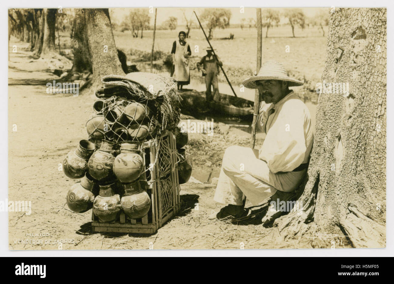 Un vendeur mexicain de bocaux, peut-être partie d'une scène de marché traditionnelle. L'image capture la pratique culturelle de la vente de poteries ou d'articles en céramique faits à la main sur les marchés mexicains. Banque D'Images