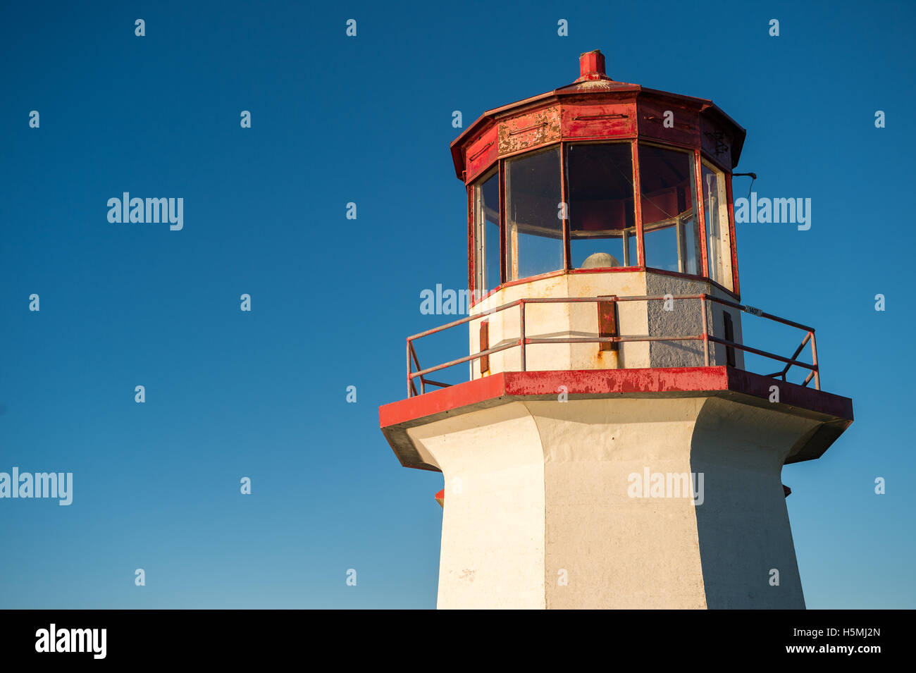 Haut d'un vieux phare rouge et blanc sur ciel bleu en Gaspésie, Québec (percé). Banque D'Images