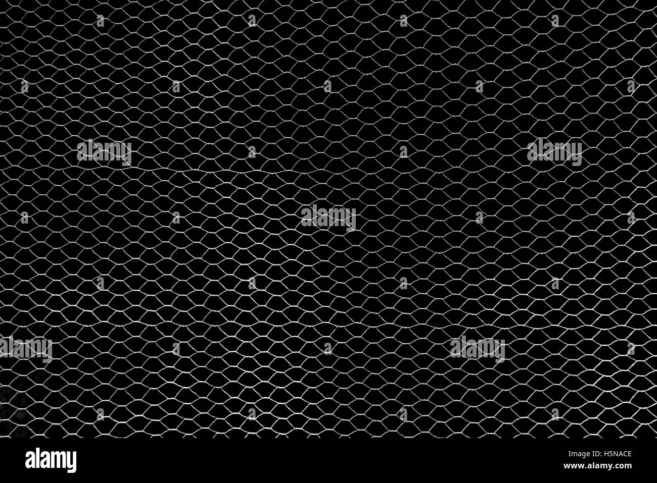En filigrane d'argent, du treillis métallique en face d'un mur noir Banque D'Images