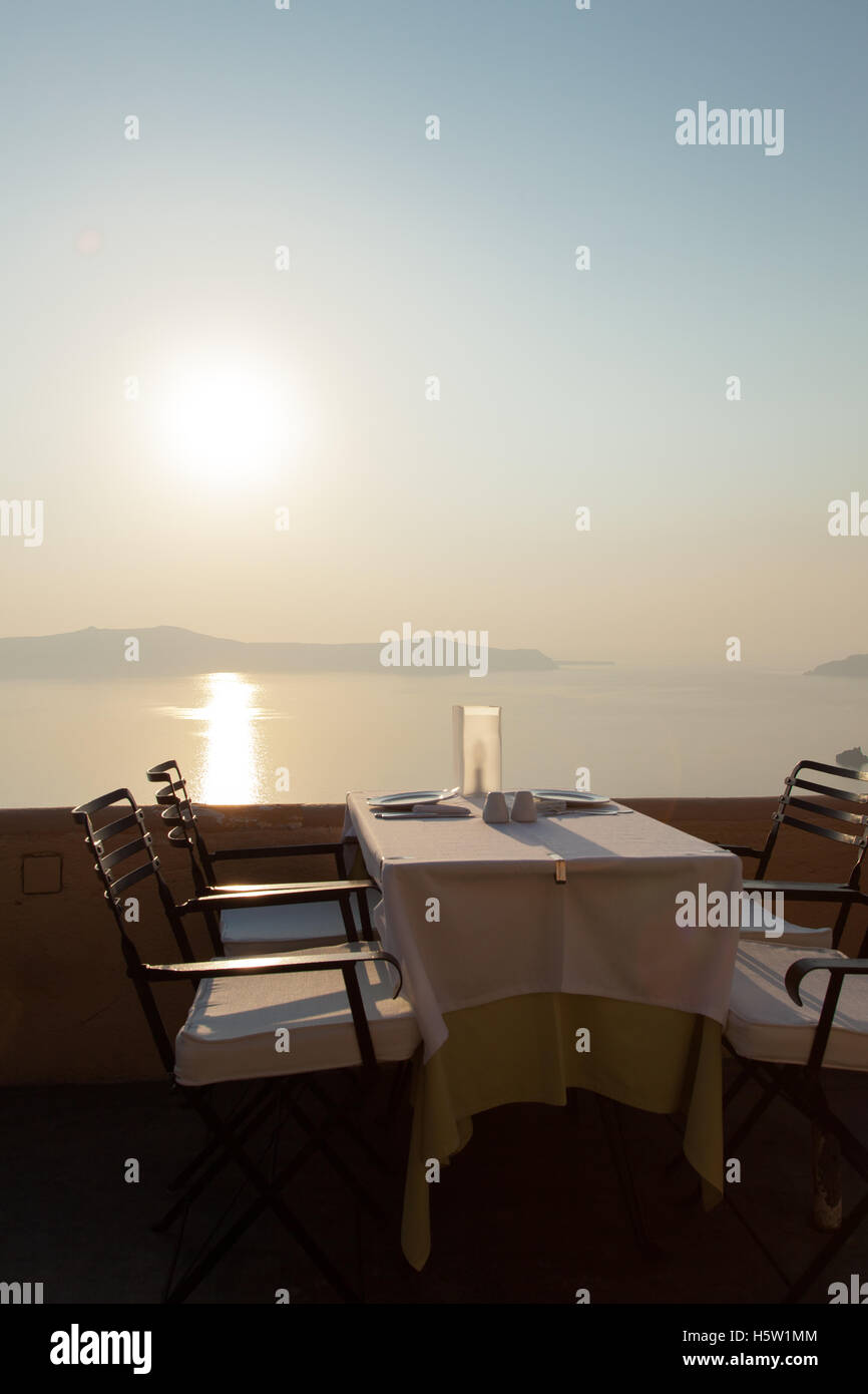 Une table est mise pour le dîner avec le coucher du soleil et d'un bleu profond de la mer et les îles. Banque D'Images