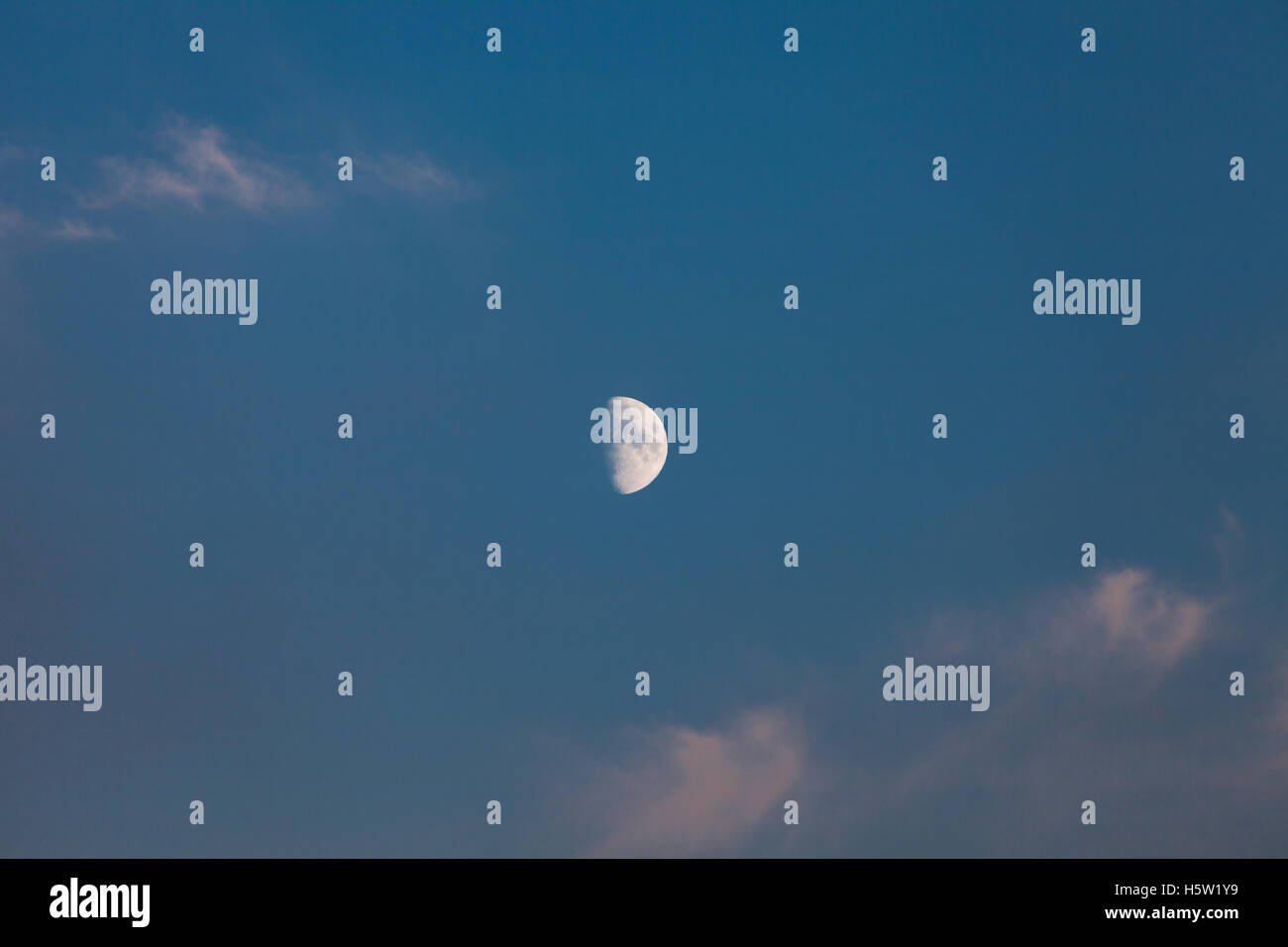 Demi-lune dans un ciel bleu avec quelques nuages Banque D'Images