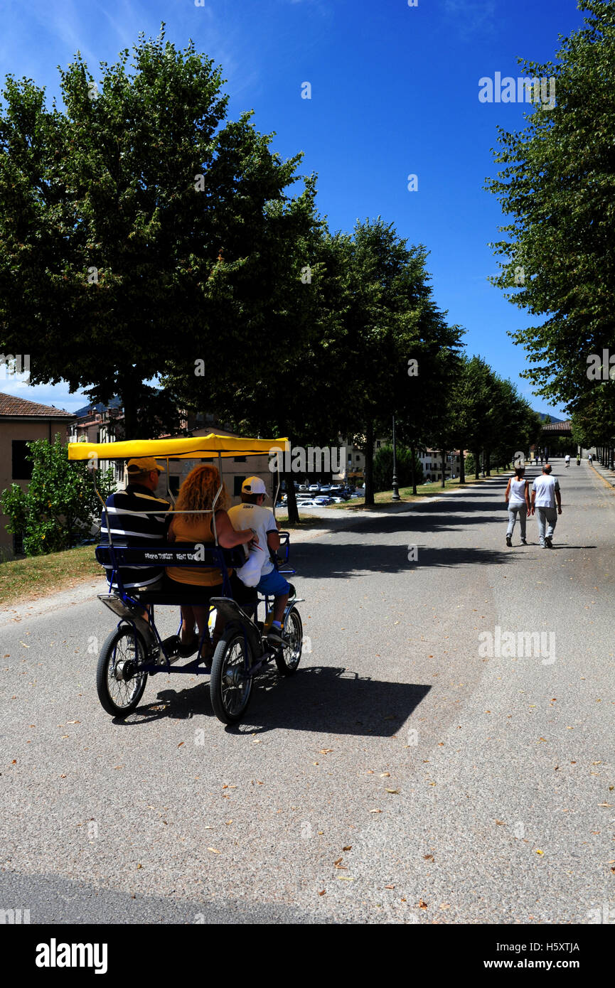 Les gens prennent un tour de ville de Lucques murs sur un pousse-pousse. Banque D'Images