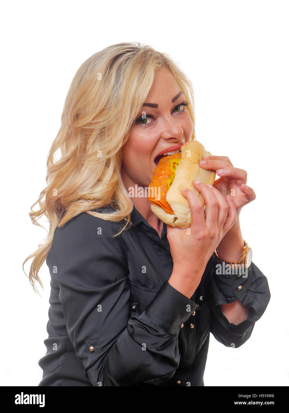 Une belle femme blonde est en train de manger un sandwich deli-styler. Banque D'Images