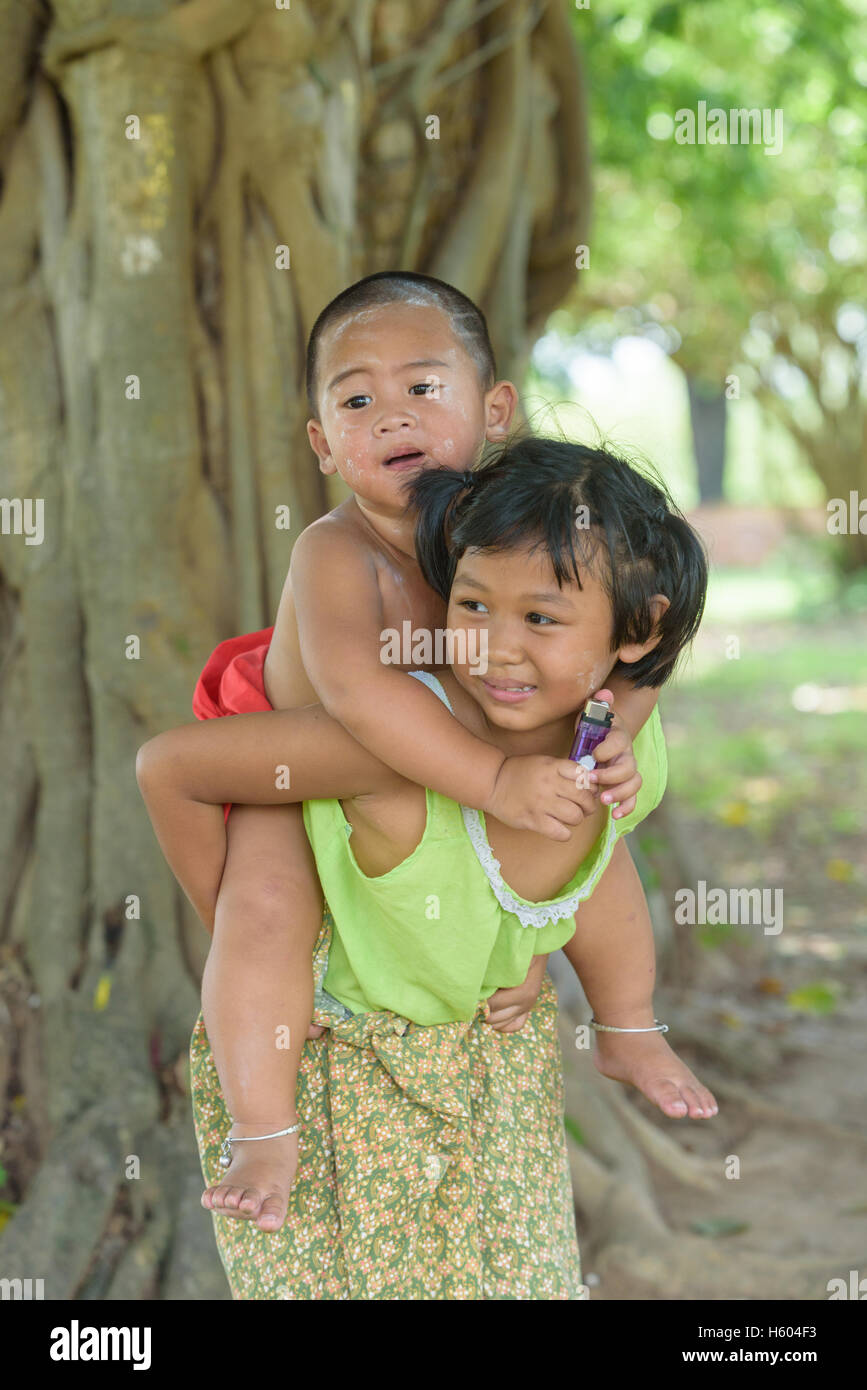 Petit garçon asiatique s'asseoir sur le dos de jeune fille ,ils sont vêtus de tenues locales thaïlandaises et jouer ensemble en plein air. Banque D'Images