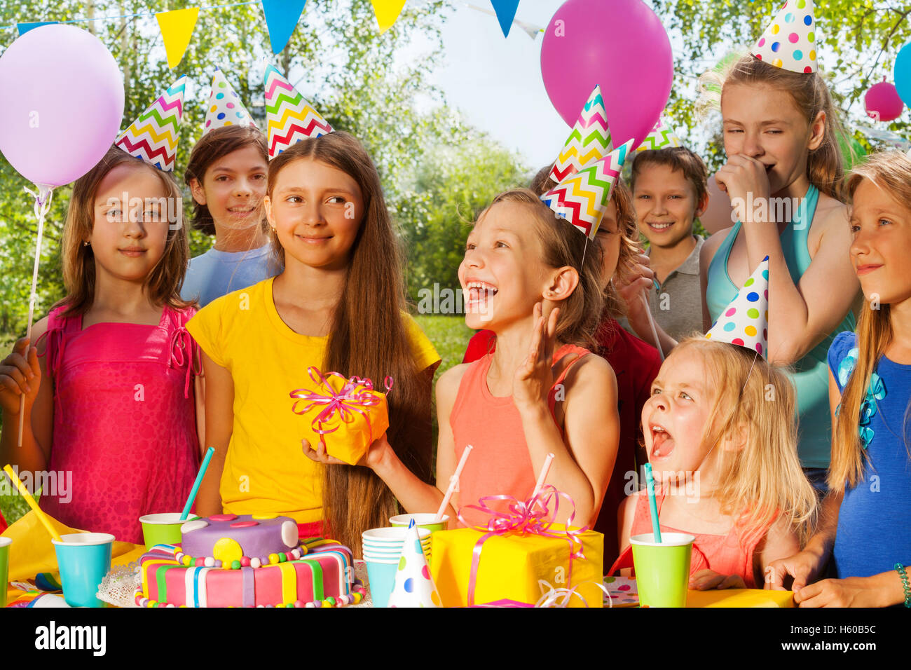 Groupe d'enfants excités félicitant fille d'anniversaire Banque D'Images
