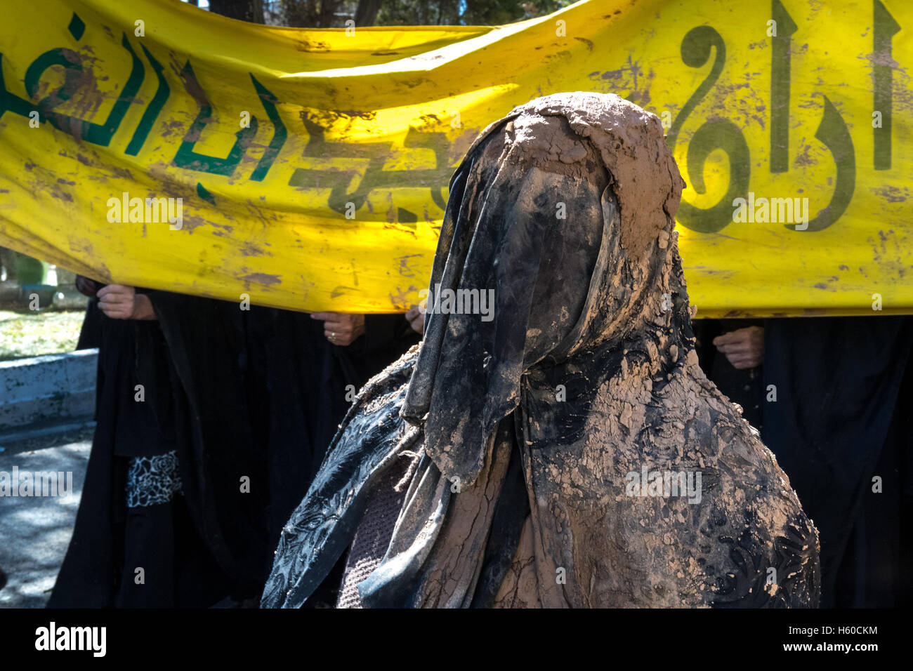 10 Muharram (Ashura), Bijar, femme portant tchador & voile intégral couvert de boue Banque D'Images