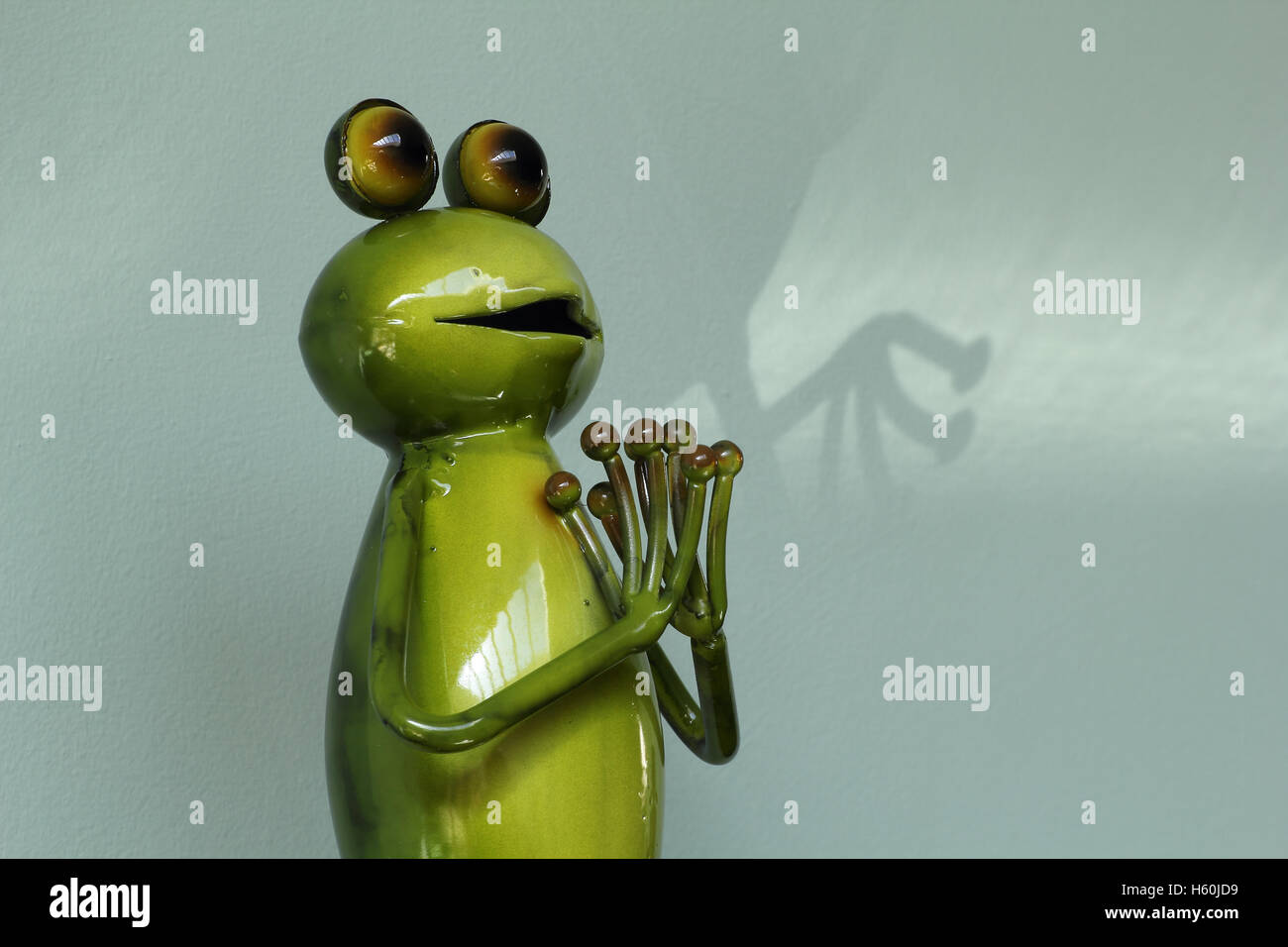 Grenouille Metal Humoristique La Figure Avec Les Mains Jointes Dans La Priere La Posture Et L Ombre Derriere Photo Stock Alamy