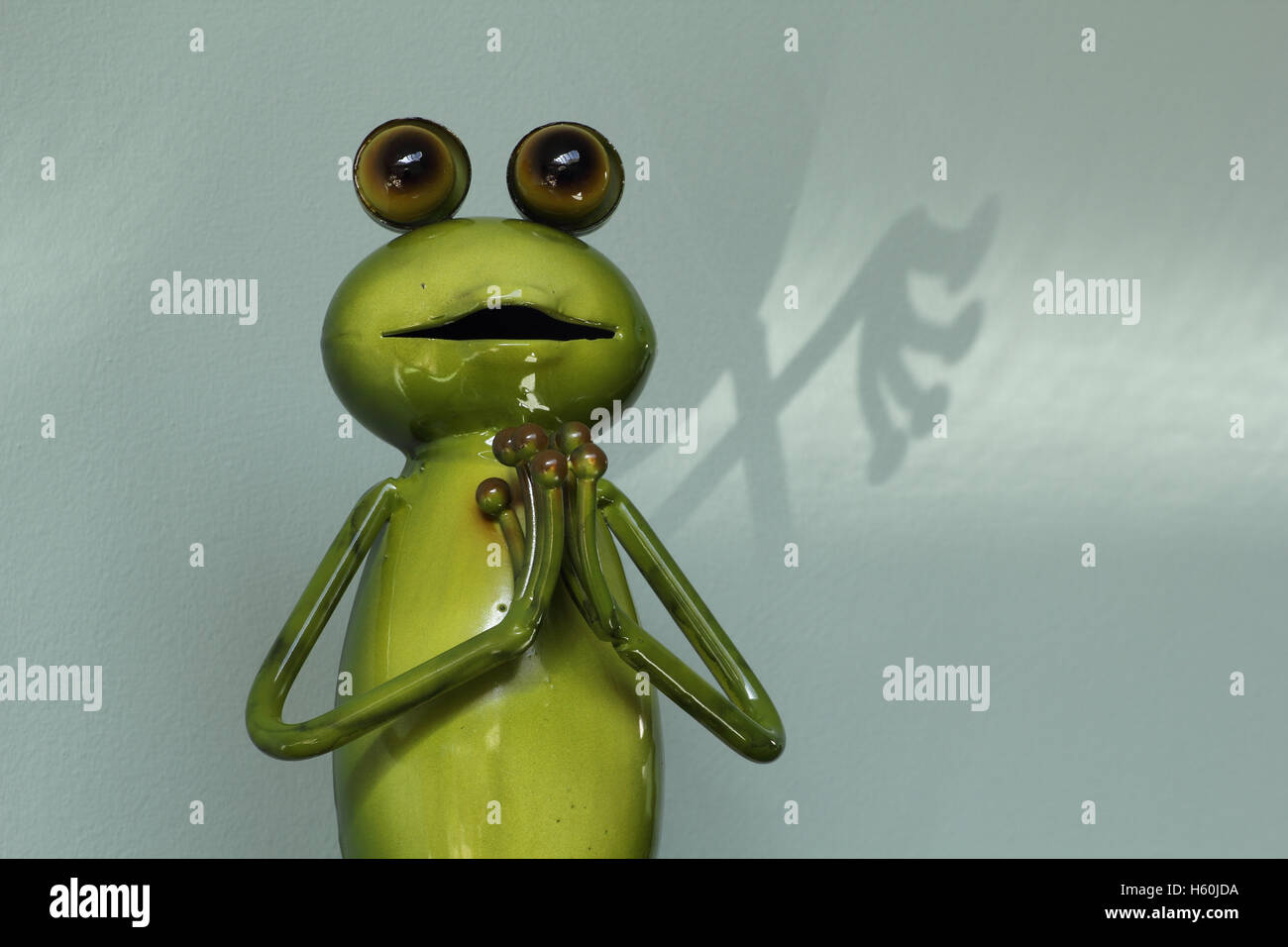 Grenouille Metal Humoristique La Figure Avec Les Mains Jointes Dans La Priere La Posture Et L Ombre Derriere Photo Stock Alamy