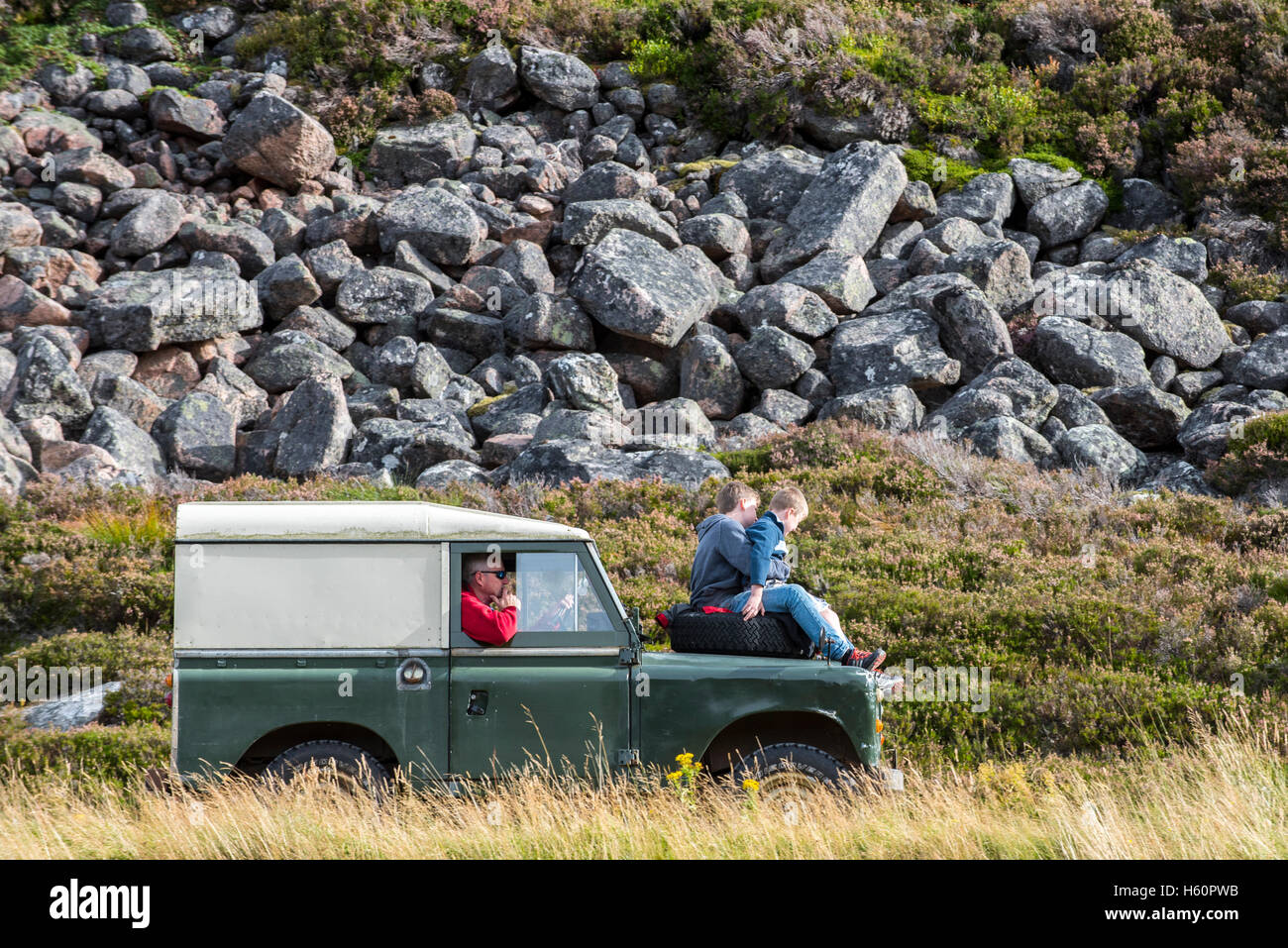 Deux enfants sur le capot de la vieille 4x4 Land Rover jeep conduite dans les montagnes Banque D'Images