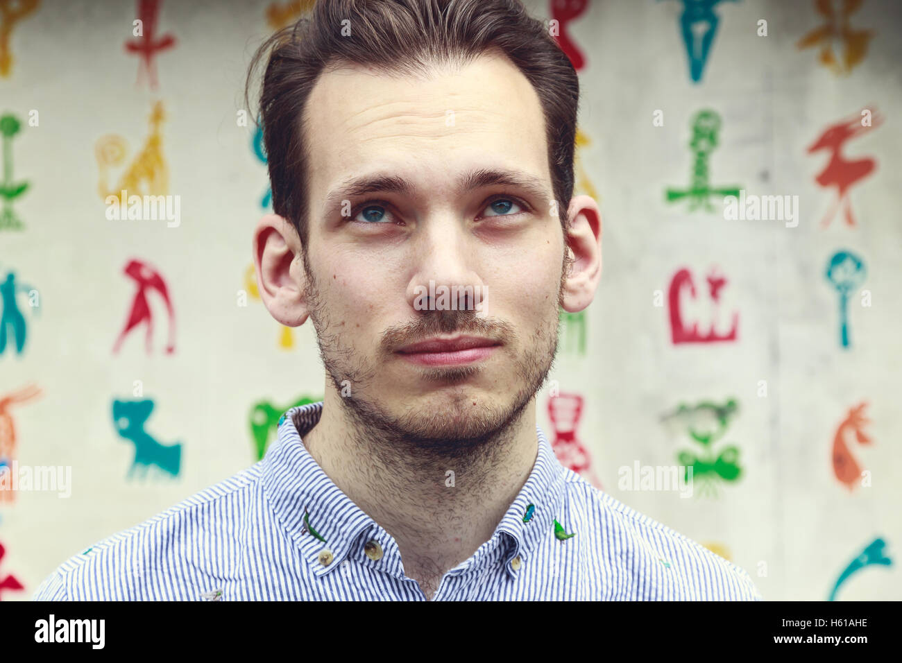 Portrait d'un jeune homme douteux devant un arrière-plan coloré funky Banque D'Images