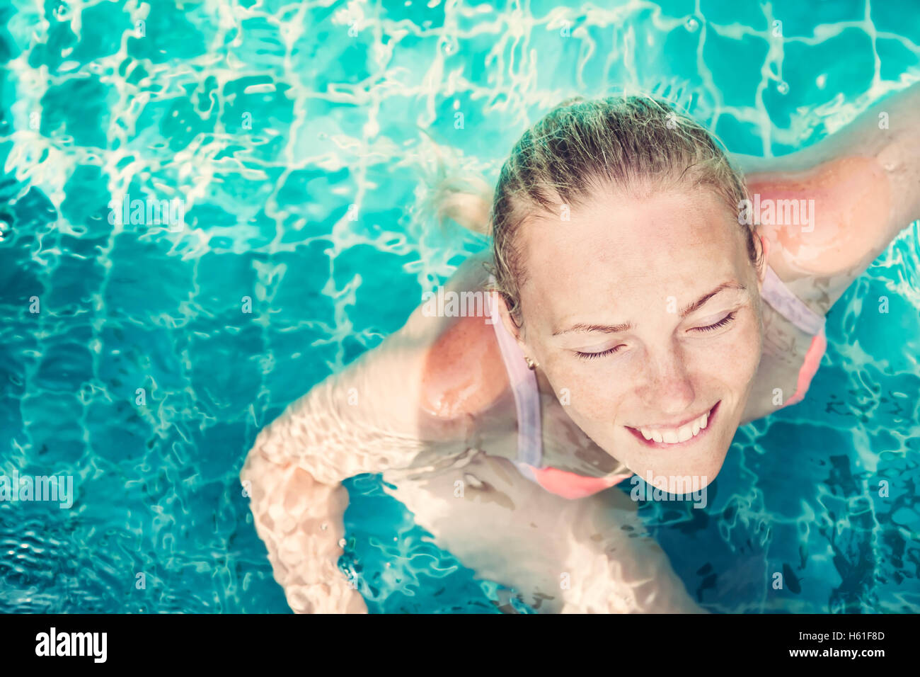 Belle jeune femme détendue avec les yeux fermés de plaisir vous baigner dans l'eau turquoise dans une piscine avec espace de copie. Vue de dessus Banque D'Images