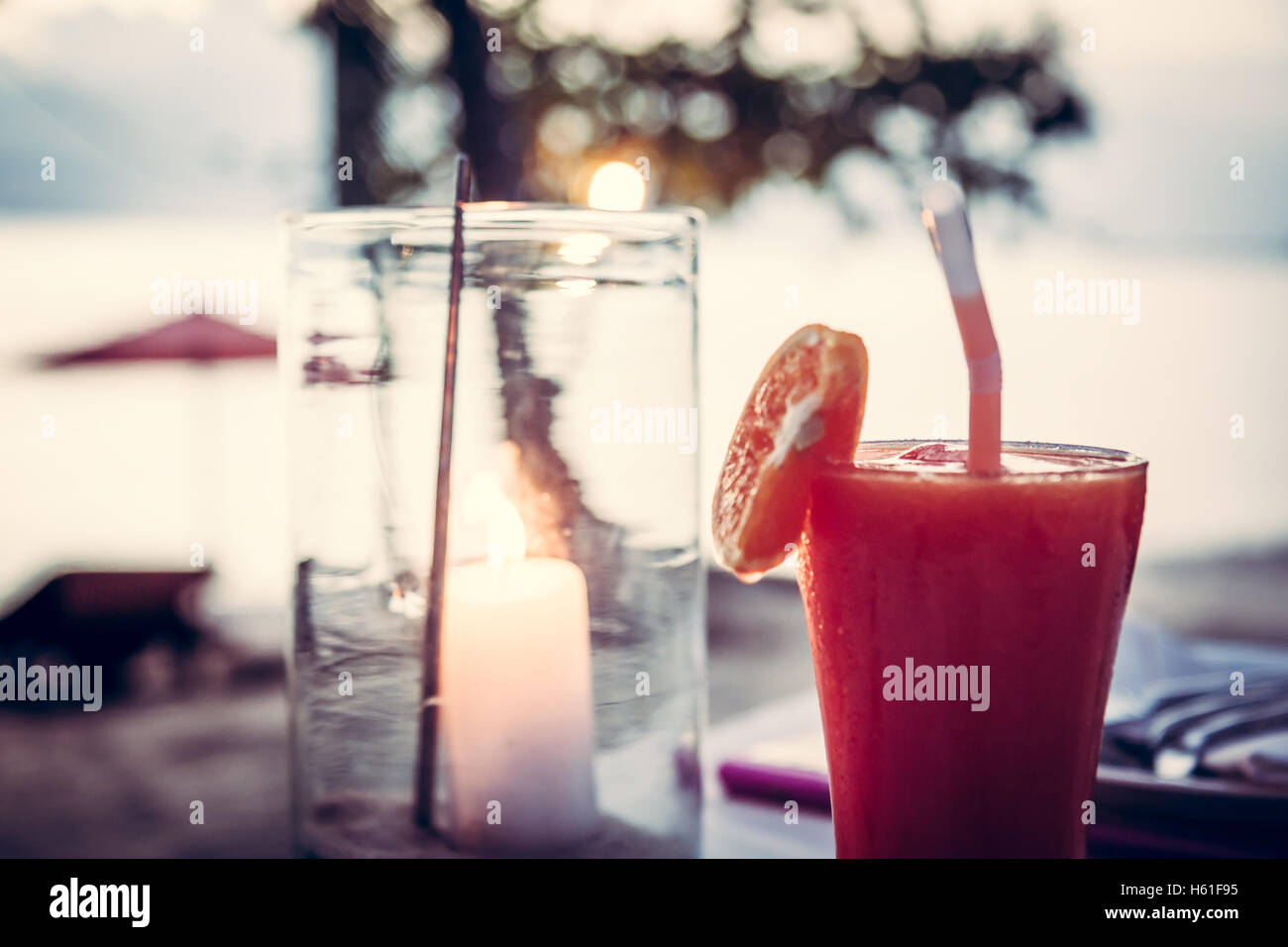 De temps pour se détendre et boire un verre. Vacances à la plage avec l'arrière-plan flou et bougie dans verre à cocktail au coucher du soleil beach café Banque D'Images