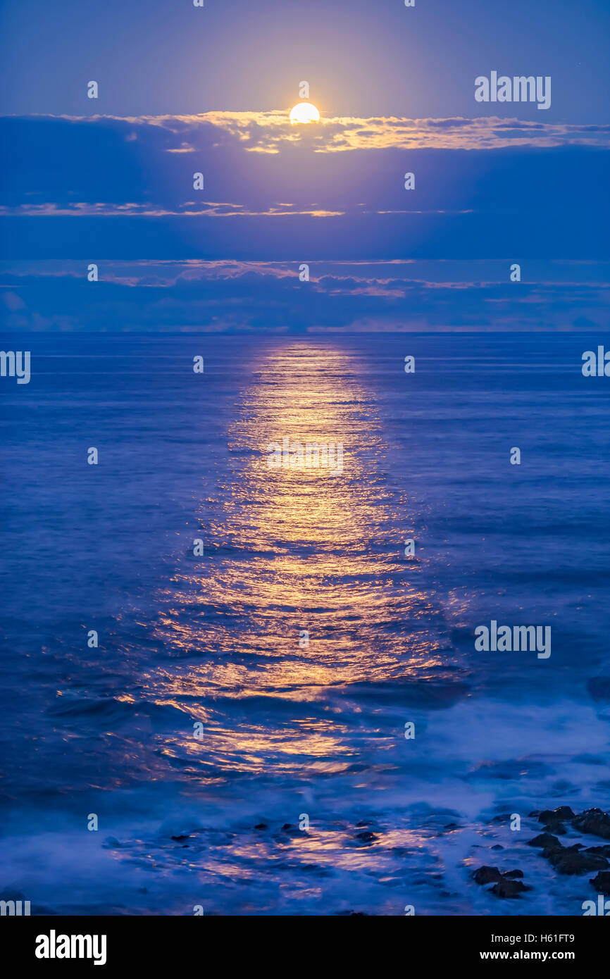 L'apogee Pleine Lune du 22 avril 2016 qui s'élève au-dessus de l'océan Pacifique et l'éclairage les eaux avec un scintillement d'or chemin de refle Banque D'Images