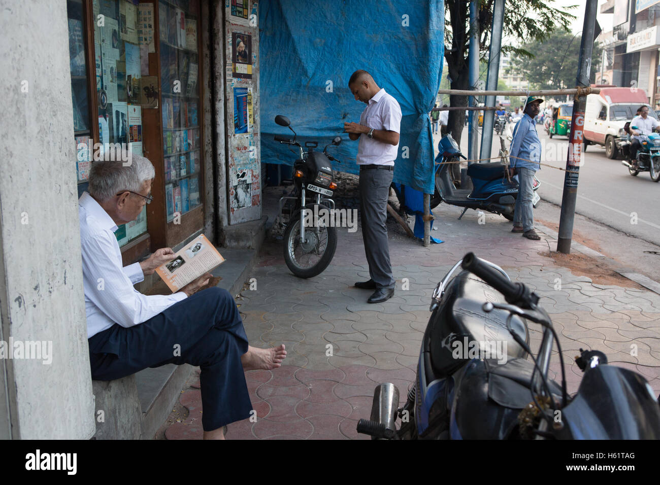 Un utilisateur lit un livre à l'extérieur de l'AA Hussain & Co librairie qui a été arrêté il y a deux ans Banque D'Images