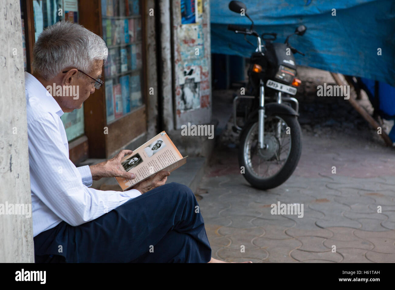Un utilisateur lit un livre à l'extérieur de l'AA Hussain & Co librairie qui a été arrêté il y a deux ans Banque D'Images