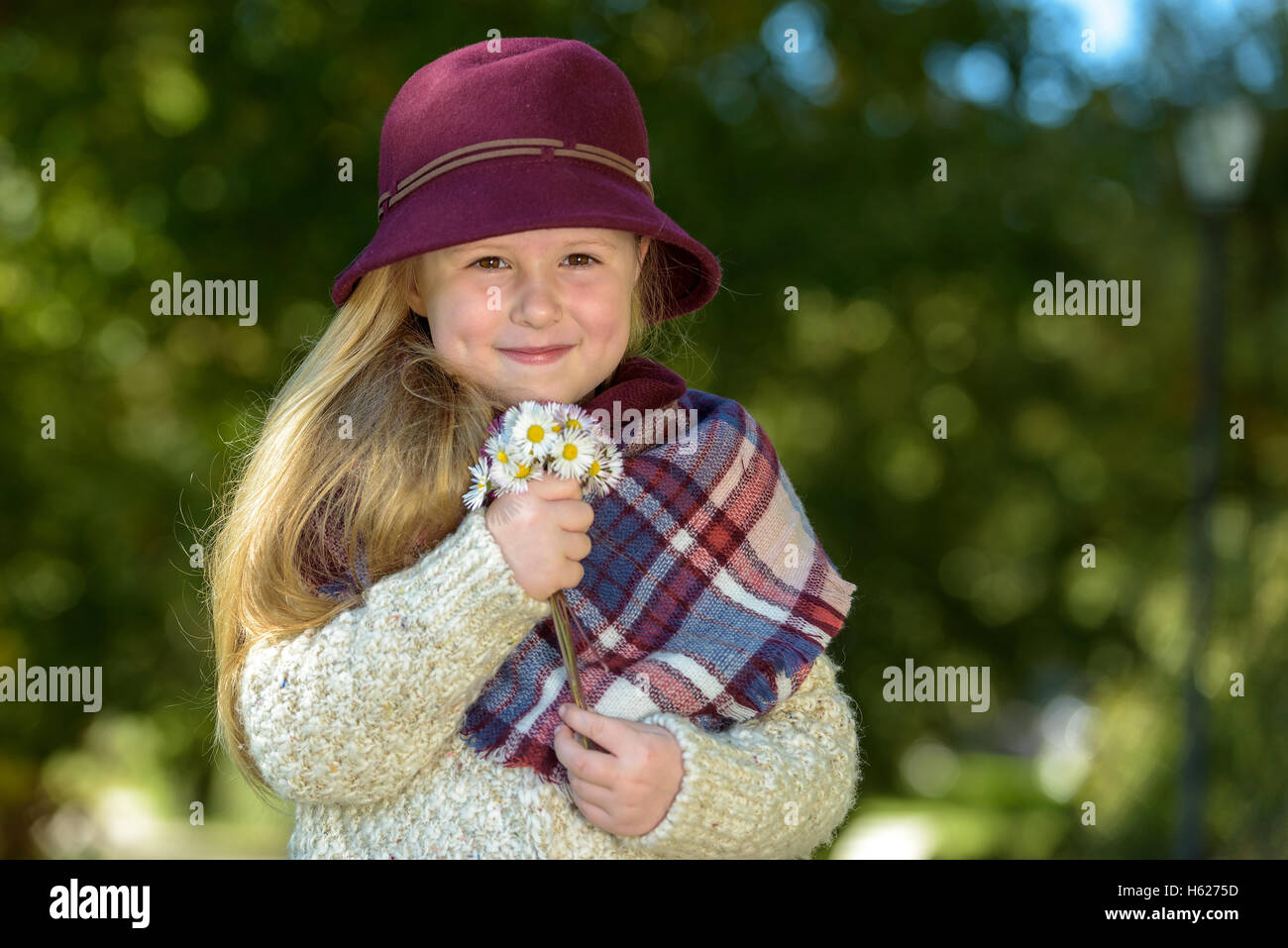 Une belle fille de bourgogne hat posant avec des fleurs dans le parc. Banque D'Images