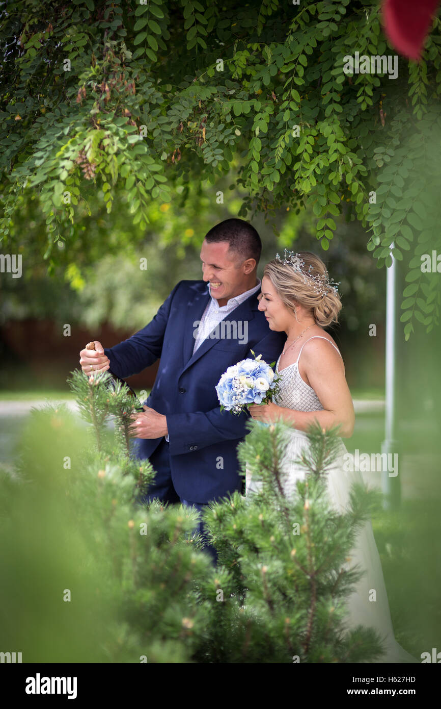 Mariée et le marié sur le mariage du champagne dans la verdure Banque D'Images