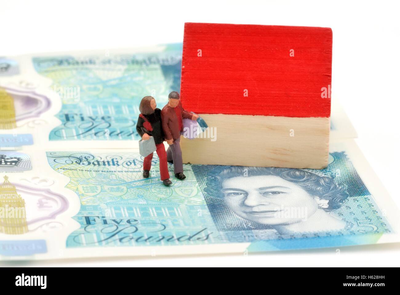 Une figurine miniature couple with shopping bags walking par une maison sur cinq notes livre Banque D'Images
