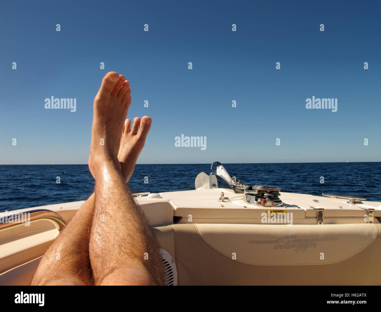 Posez vos pieds - une paire de pieds sur le devant d'un bateau avec un ciel bleu derrière, sur la mer des Caraïbes à la Barbade. Vacances, vacances Banque D'Images