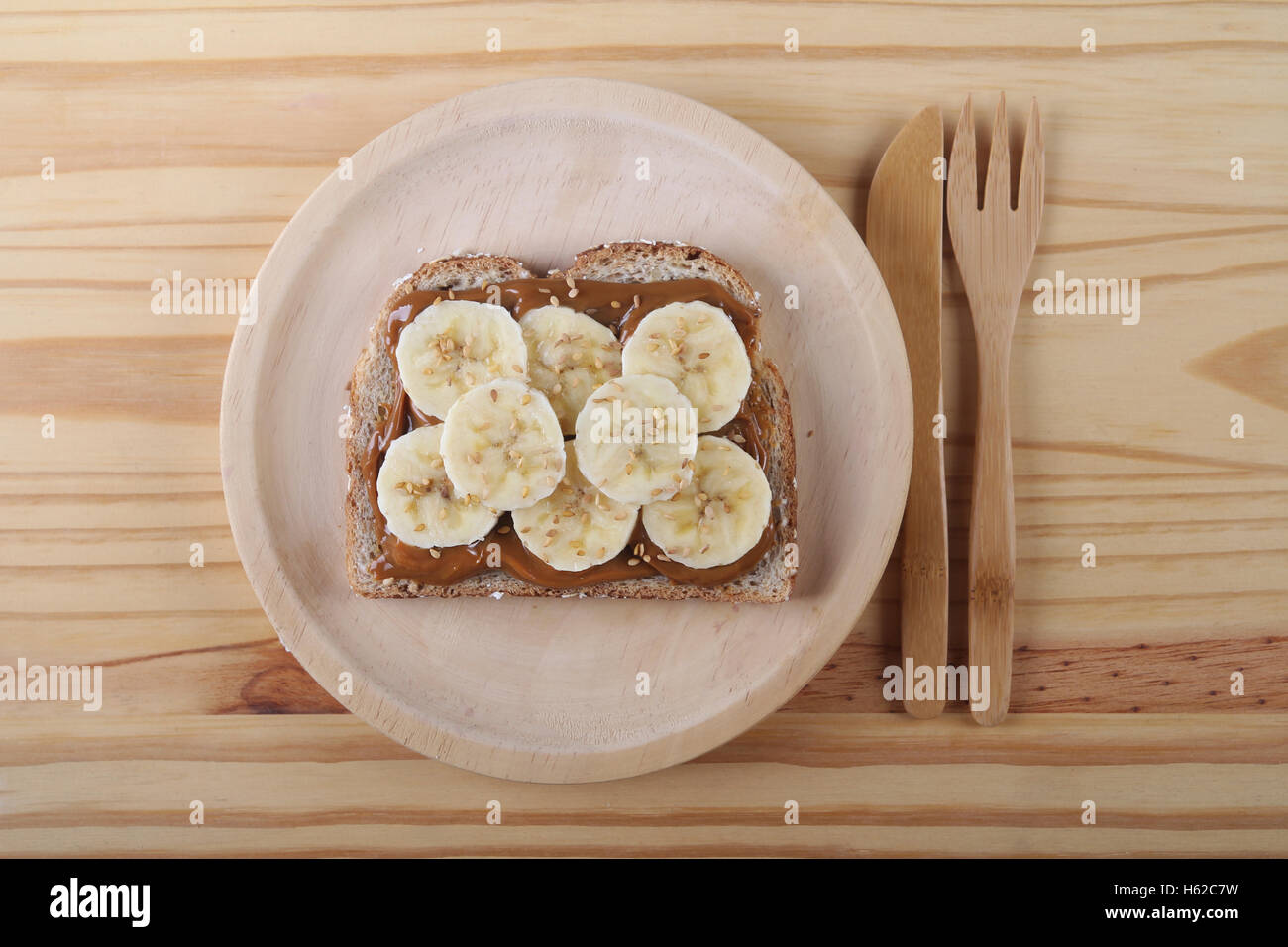 Toast de Dulce de Leche, tranches de banane et graines de sésame sur plaque de bois et une table Banque D'Images