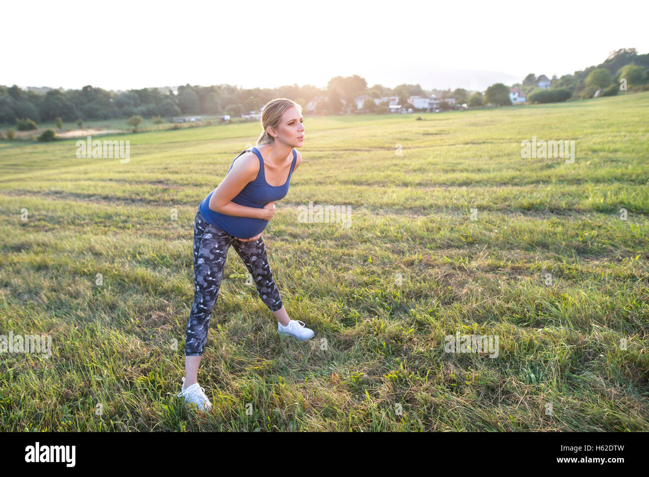 Pregnant woman standing in field faisant des exercices Banque D'Images