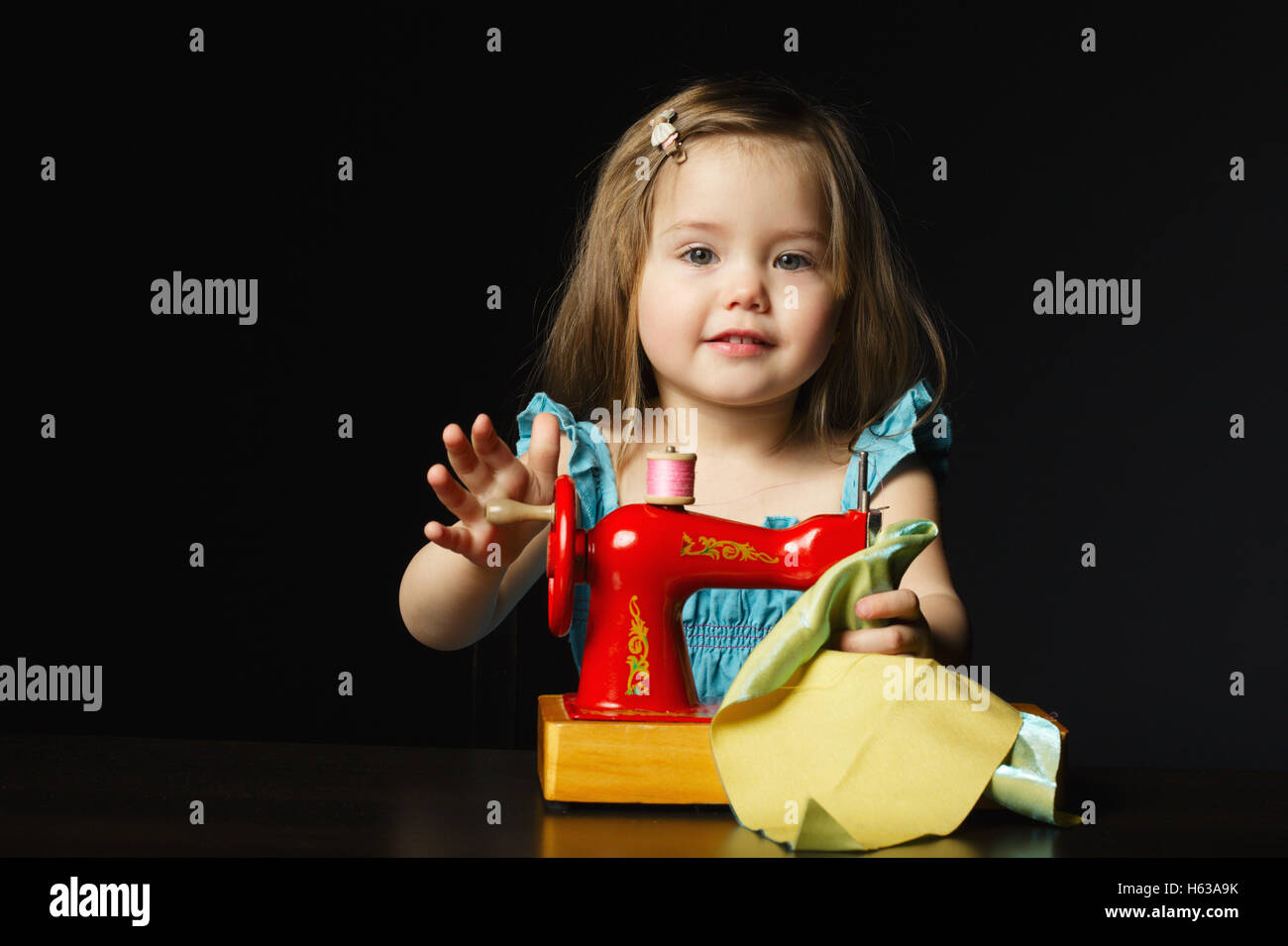 Petite fille joue avec la machine à coudre Banque D'Images